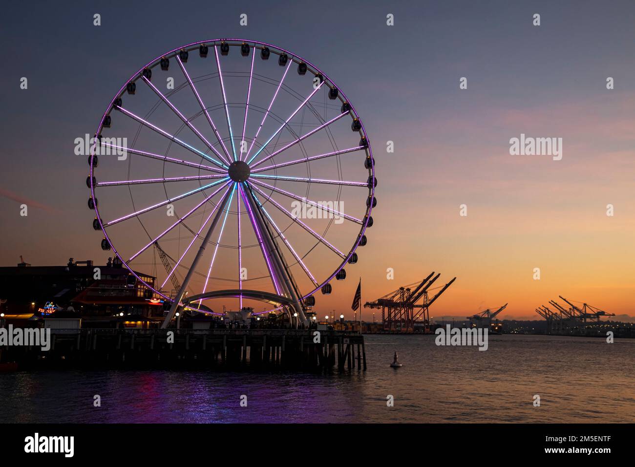 WA22872-00...WASHINGTON - das Seattle Great Wheel bei Sonnenuntergang, an der Elliott Bay mit dem Hafen von Seattle in der Ferne. Stockfoto