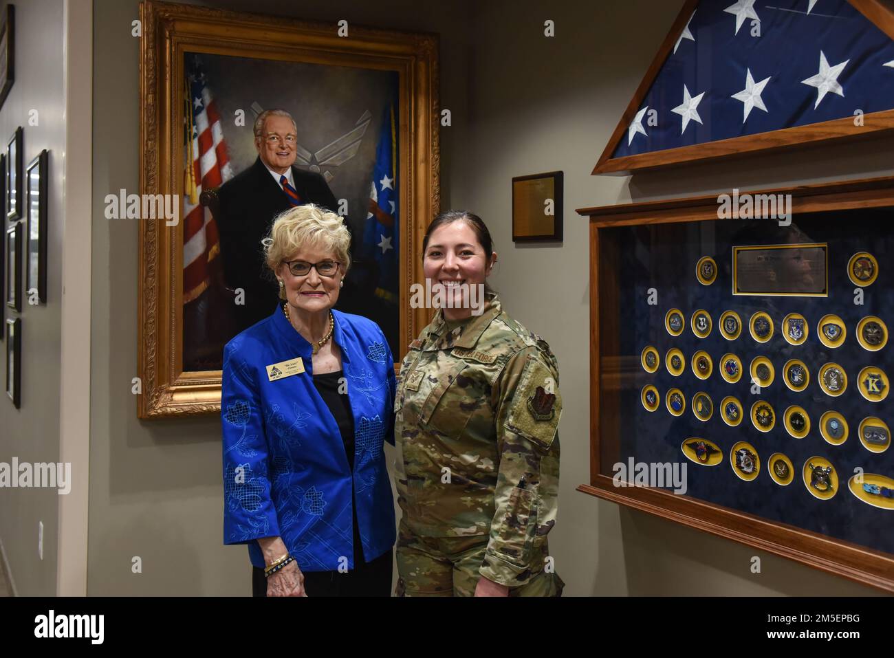 Dr. Lucy Greene, links, steht für U.S. Air Force Staff Sergeant Kyana Mamahua, 74. Fighter Squadron Intelligence Uncommissioned Officer, direkt vor einem Porträt von Parker Greene, nachdem Mamahua den Parker and Dr. Lucy Greene Service Award 2021 verliehen wurde, am 8. März 2022, auf dem Luftwaffenstützpunkt Moody, Georgia. Die Auszeichnung wurde von dem ständigen gemeinnützigen Dienst des Greene inspiriert. Stockfoto