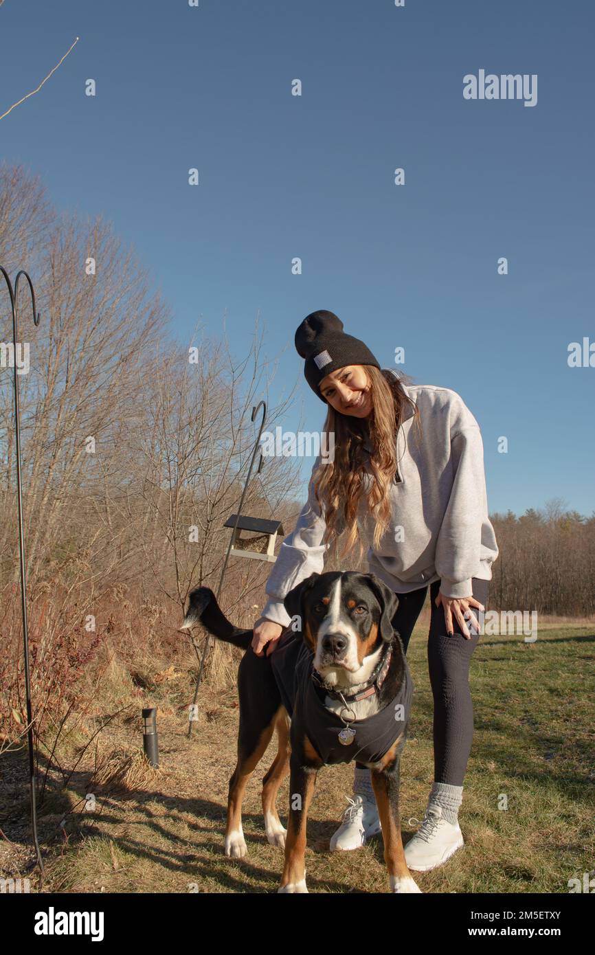 Ein Mädchen mit ihrem schweizer Berghund läuft draußen am Waldrand in New Hampshire, USA Stockfoto