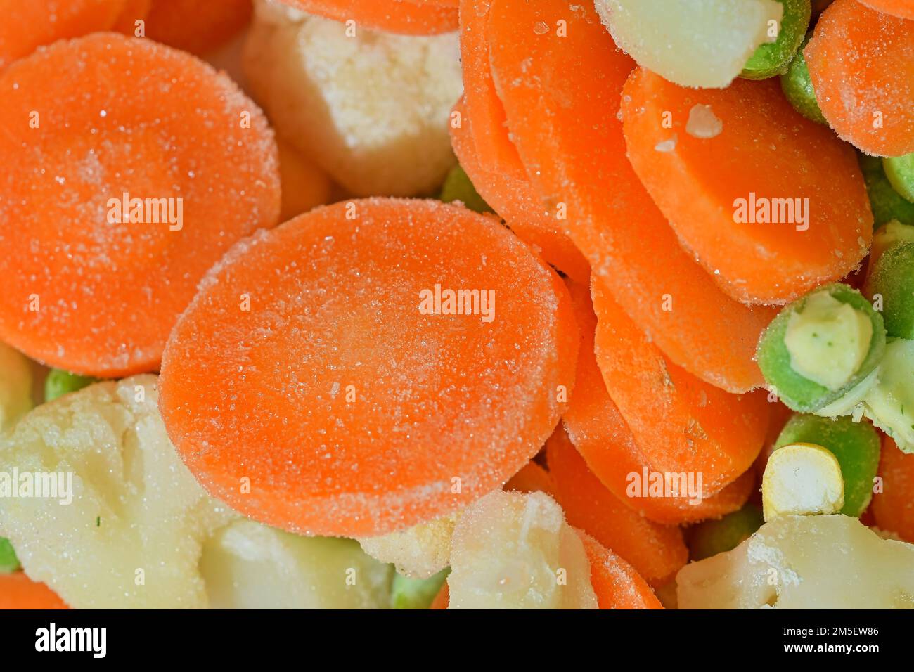 Nahaufnahme des Suppengemüses mit Karotten, Erbsen, Blumenkohl und Mais. Textur von Tiefkühlsuppenprüfständen. Gefrorenes Suppengemüse. Flache Ausführung, Stockfoto