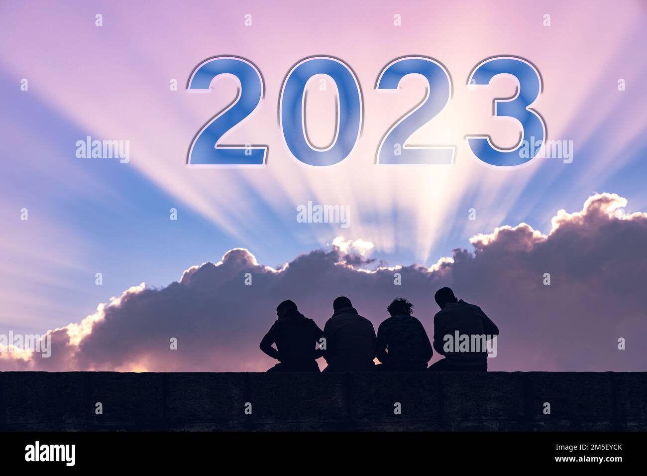 Frohes neues Jahr 2023, Lichtstrahlen am bewölkten Himmel, Rückblick auf die Silhouetten sitzender Menschen. Stockfoto
