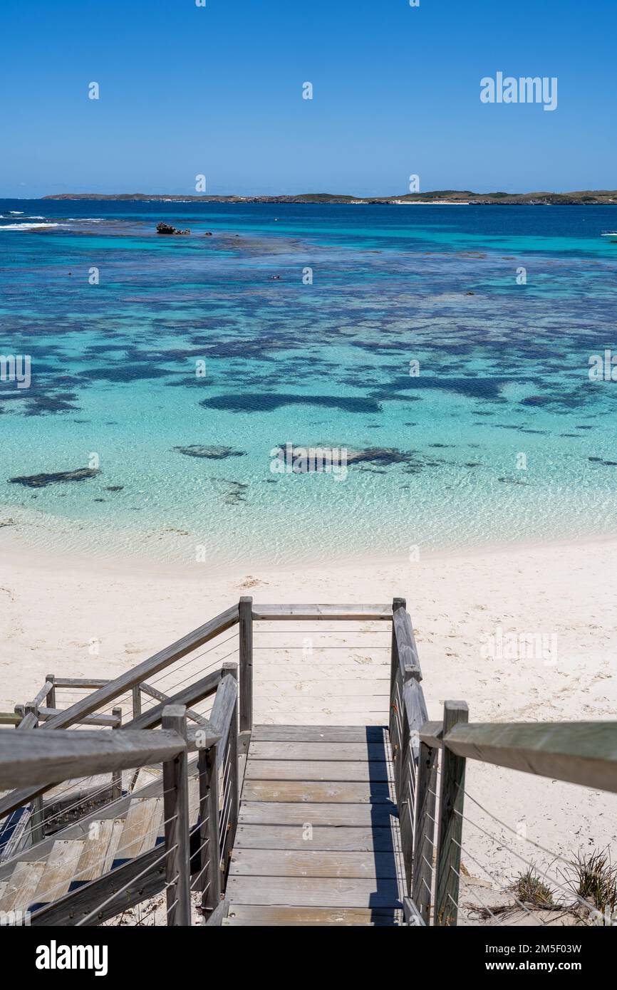 Ein vertikales Hochwinkelfoto einer hölzernen Treppe an der Küste eines Ozeans an einem sonnigen Tag Stockfoto