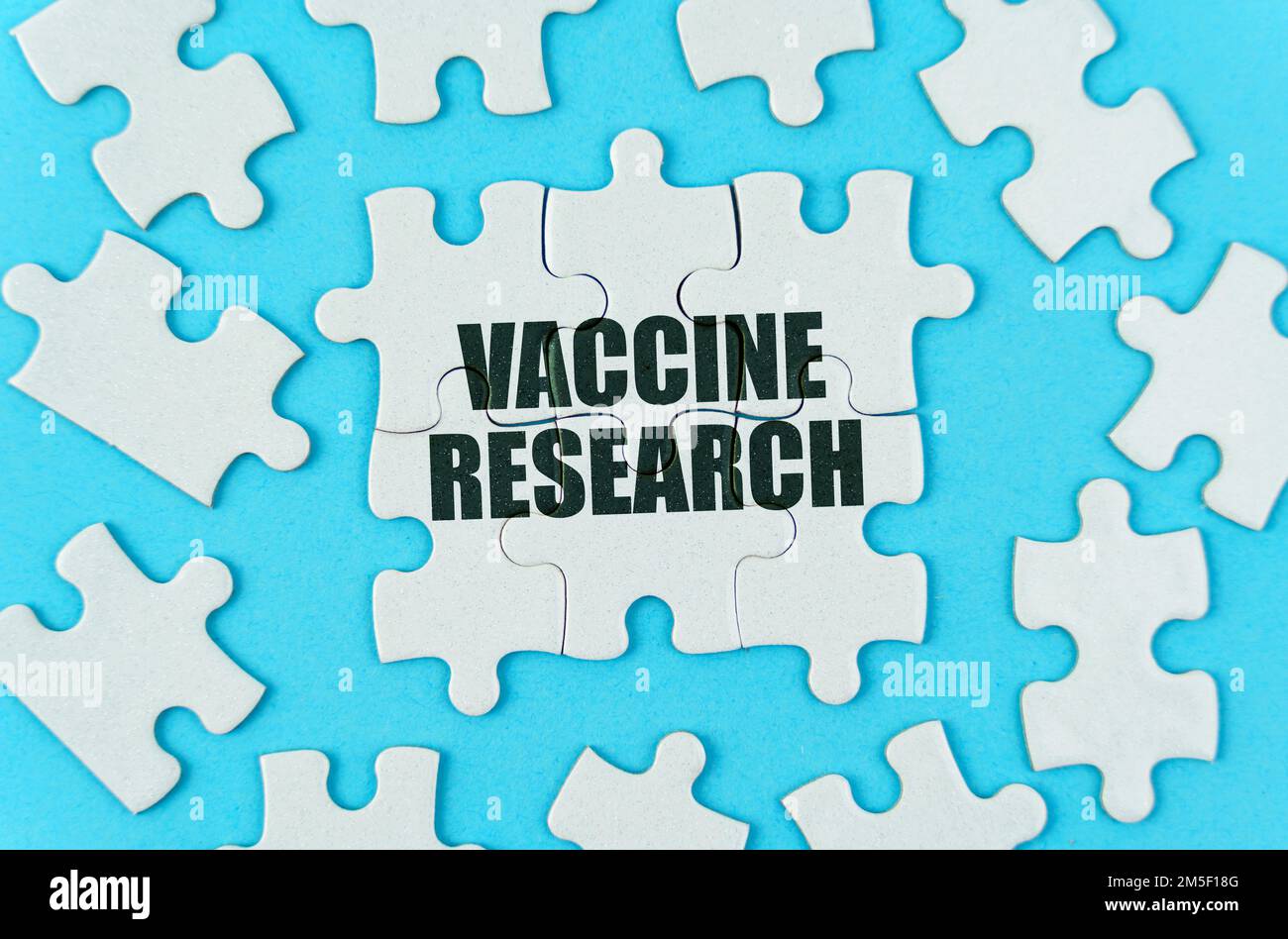 Medizinisches Konzept. Auf blauem Hintergrund sind weiße Puzzles mit der Inschrift - Vaccine Research Stockfoto