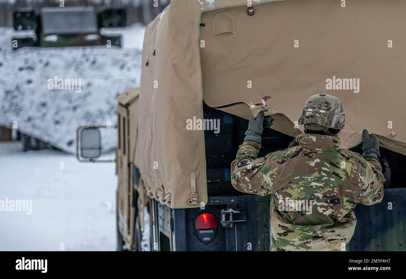 EIN US-AMERIKANISCHER Ein Soldat, dem 1. Bataillon zugeteilt, 265. Air Defense Artillery Regiment, Florida Army National Guard, hebt eine Tarnung auf der Rückseite eines Humvees während der Übung ARCTIC EDGE 2022 am Eielson Air Force Base, Alaska, 10. März 2022. Arctic Edge ist die größte gemeinsame Übung in Alaska. Neben Mitgliedern der kanadischen Streitkräfte werden etwa 1.000 US-Militärangehörige geschult. Stockfoto