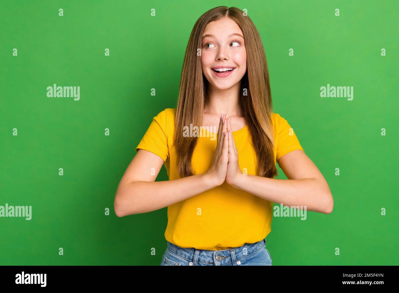 Foto eines positiven, netten Mädchens, ein Lächeln, Hände, die auf den grünen Hintergrund zeigen, wie ein leerer Raum aussieht Stockfoto