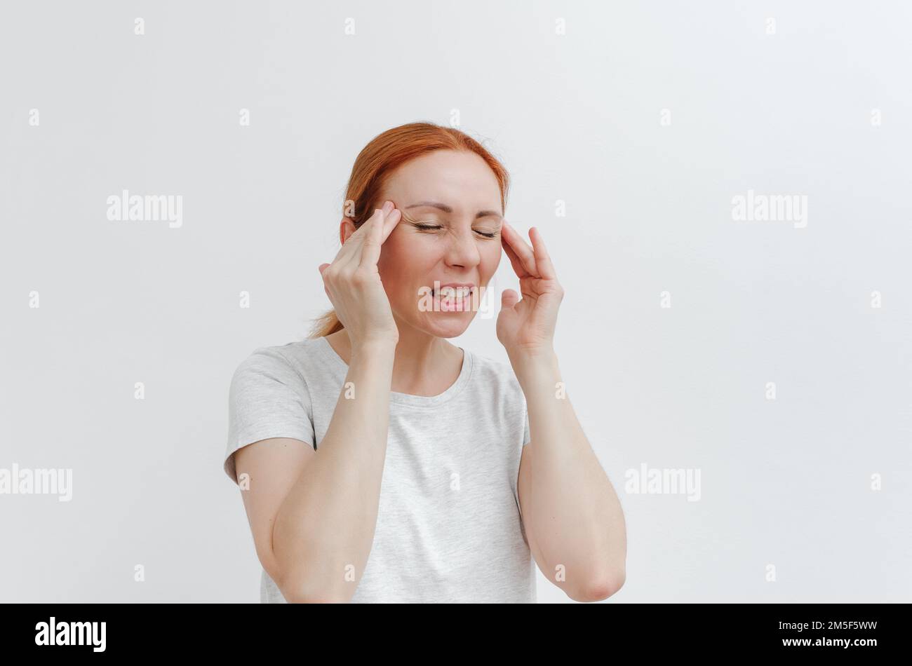 Junge Frau mit Kopfschmerzen. Kopfschmerz, Tempel. Kopfschmerzen, Migräne, Augenschmerzen. Weißer Hintergrund. Stockfoto