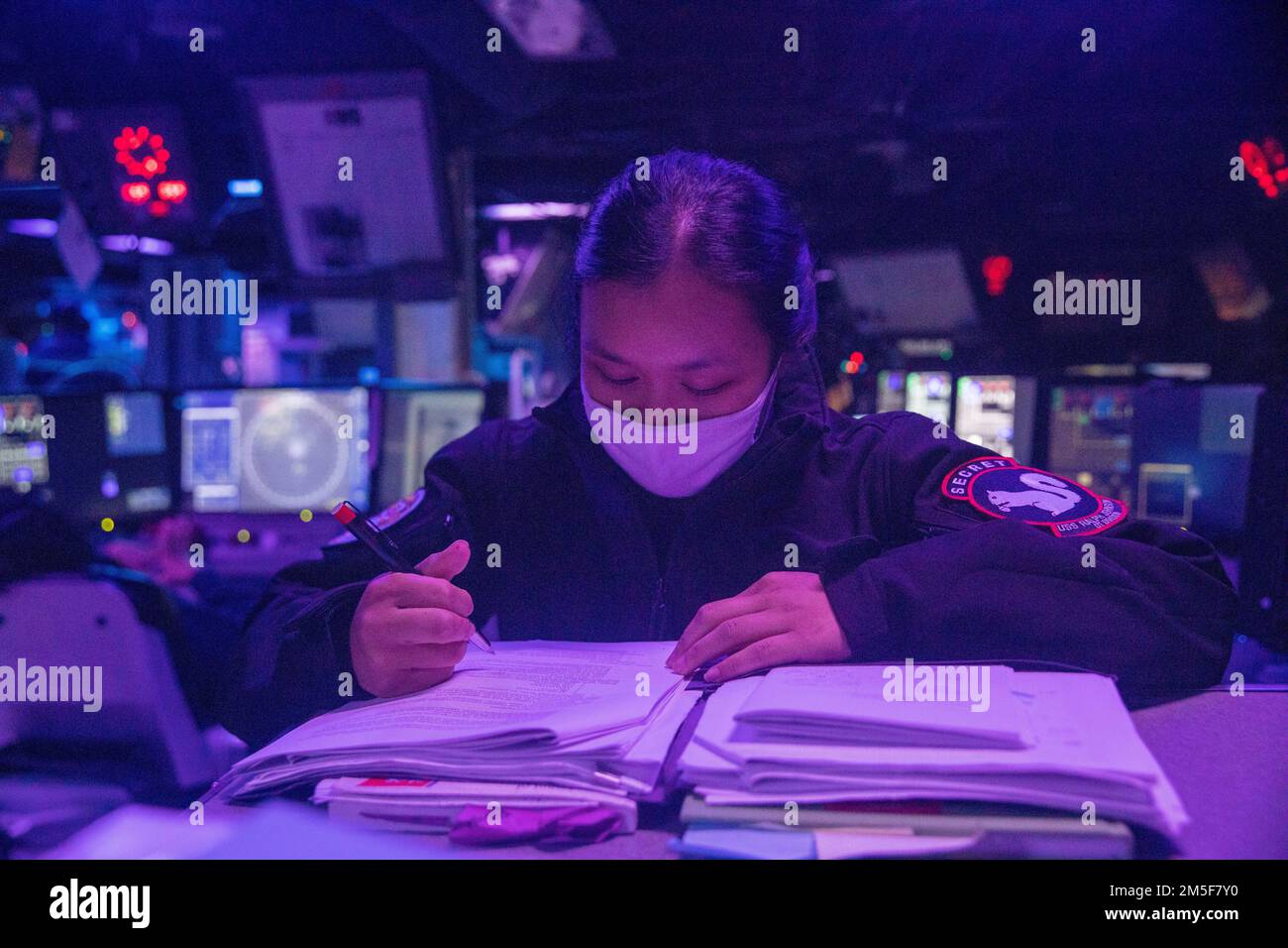 PHILIPPINE SEA (10. März 2022) Fähnrich Sydney Tse aus Bayonne, N.J., erledigt Papierkram, während er Wache in der Kampfeinformationszentrale an Bord der Arleigh-Burke-Klasse-Guided-Missile Destroyer USS Ralph Johnson (DDG 114) hält. Ralph Johnson ist der Task Force 71/Destroyer Squadron (DESRON) 15, dem größten nach vorn verlegten DESRON der Marine, und der Hauptstreitkraft der US-7.-Flotte zugewiesen. Stockfoto