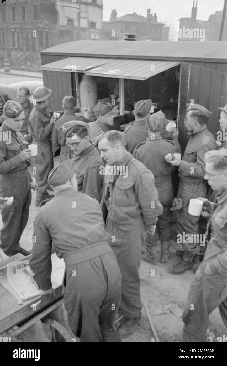 Männer des Pioneer Corps versammeln sich in einer WVS-Kantine und entspannen sich mit Tee und Brötchen nach einem Morgen, an dem Schutt und Trümmer nach einem Luftangriff in dieser Gegend von London, 1941, geräumt wurden. Stockfoto