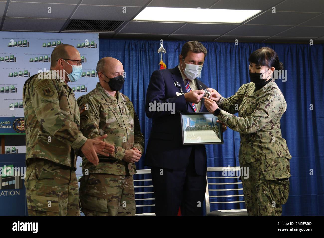 BUFFALO, NEW YORK. - AUS DEN USA Leutnant Commander Der Marine. Diana Tran-Yu, die Leiterin eines militärischen medizinischen Teams, überreicht Tom Quatroche, Präsident und CEO des Erie County Medical Center, eine Münze und ein Gruppenfoto und unterstützt gleichzeitig die COVID-Response-Operationen des ECMC in Buffalo, New York, am 11. März 2022. Nördliches Kommando, durch die USA Army North ist nach wie vor entschlossen, das Verteidigungsministerium flexibel bei der COVID-Reaktion der gesamten Regierung zu unterstützen. Stockfoto
