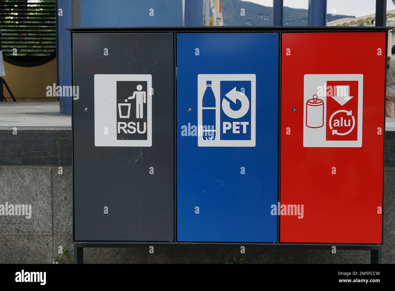 Drei Abfalltrennbehälter in Schwarz, Blau und Rot für festen Siedlungsabfall, Kunststoff und Aluminium mit Beschriftung in italienischer Sprache. Stockfoto