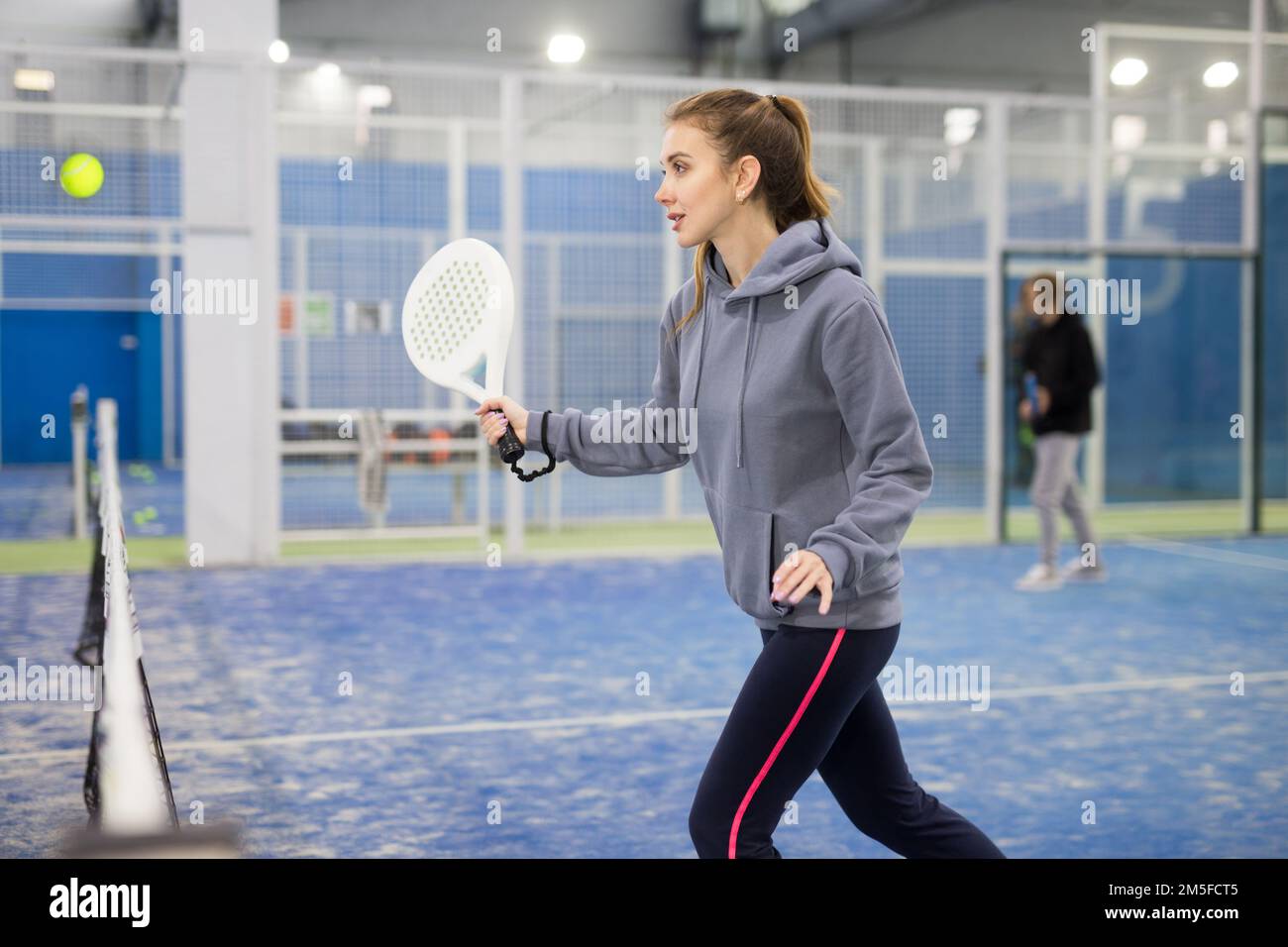Frau, die beim Padel auf dem Platz den Ball servierte Stockfoto