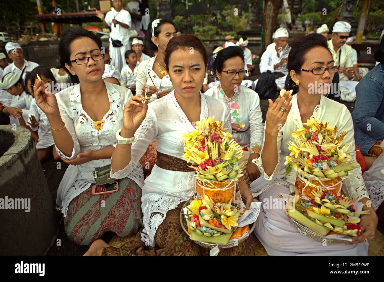 Ein balinesischer Clan, der ein Ritual durchführt, um die Geister seiner verstorbenen Familienmitglieder zu ehren und zu reinigen, an einem Strand in der Nähe des Goa Lawah Tempels in Dawan, Klungkung, Bali, Indonesien. Stockfoto