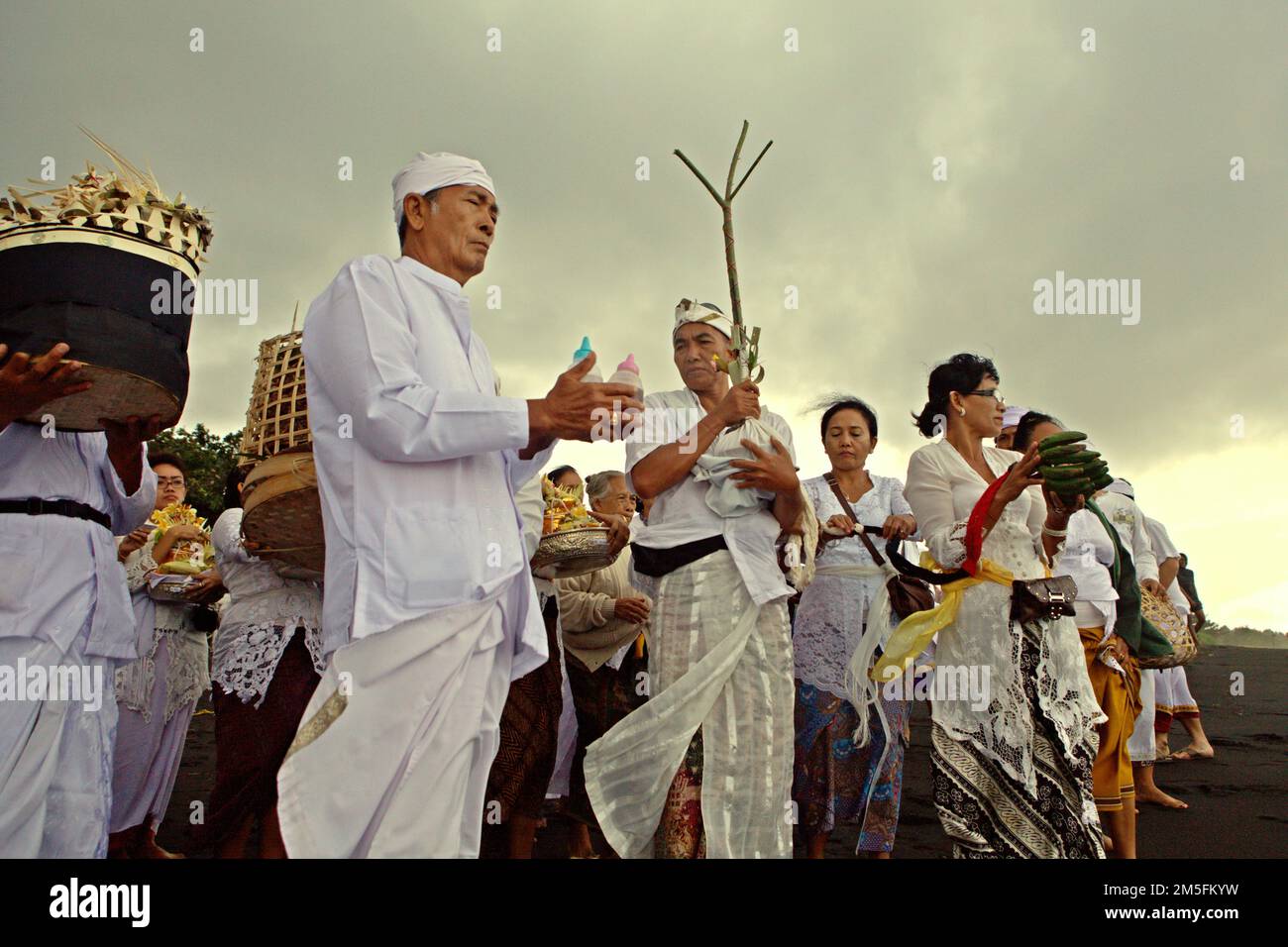 Ein balinesischer Clan bereitet sich auf ein Ritual vor, um die Geister ihrer verstorbenen Familienmitglieder zu ehren und zu reinigen, an einem Strand in der Nähe des Goa Lawah Tempels in Dawan, Klungkung, Bali, Indonesien. Stockfoto
