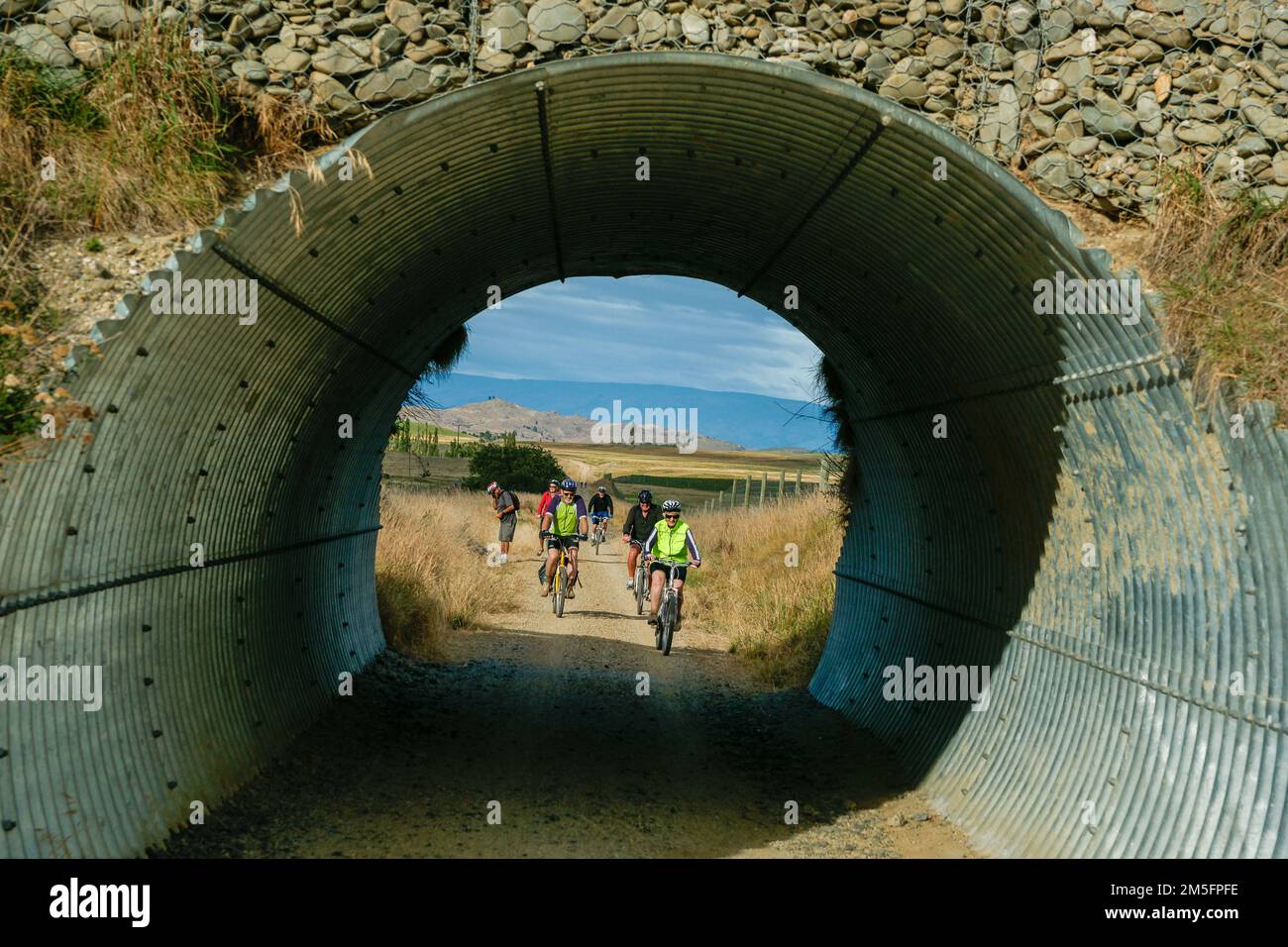 Otago Neuseeland - März 1 2010; Radfahrer, die durch einen Tunnel unter einer Brücke auf dem Central Otago Rail Trail fahren Stockfoto