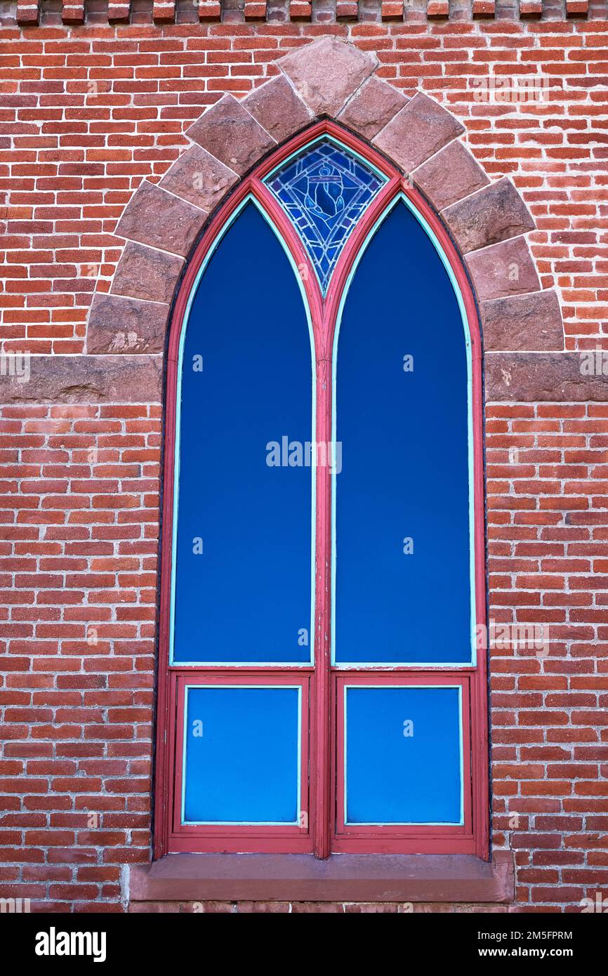 Altes Bogenfenster mit getöntem Glas in einem Backsteingebäude Stockfoto