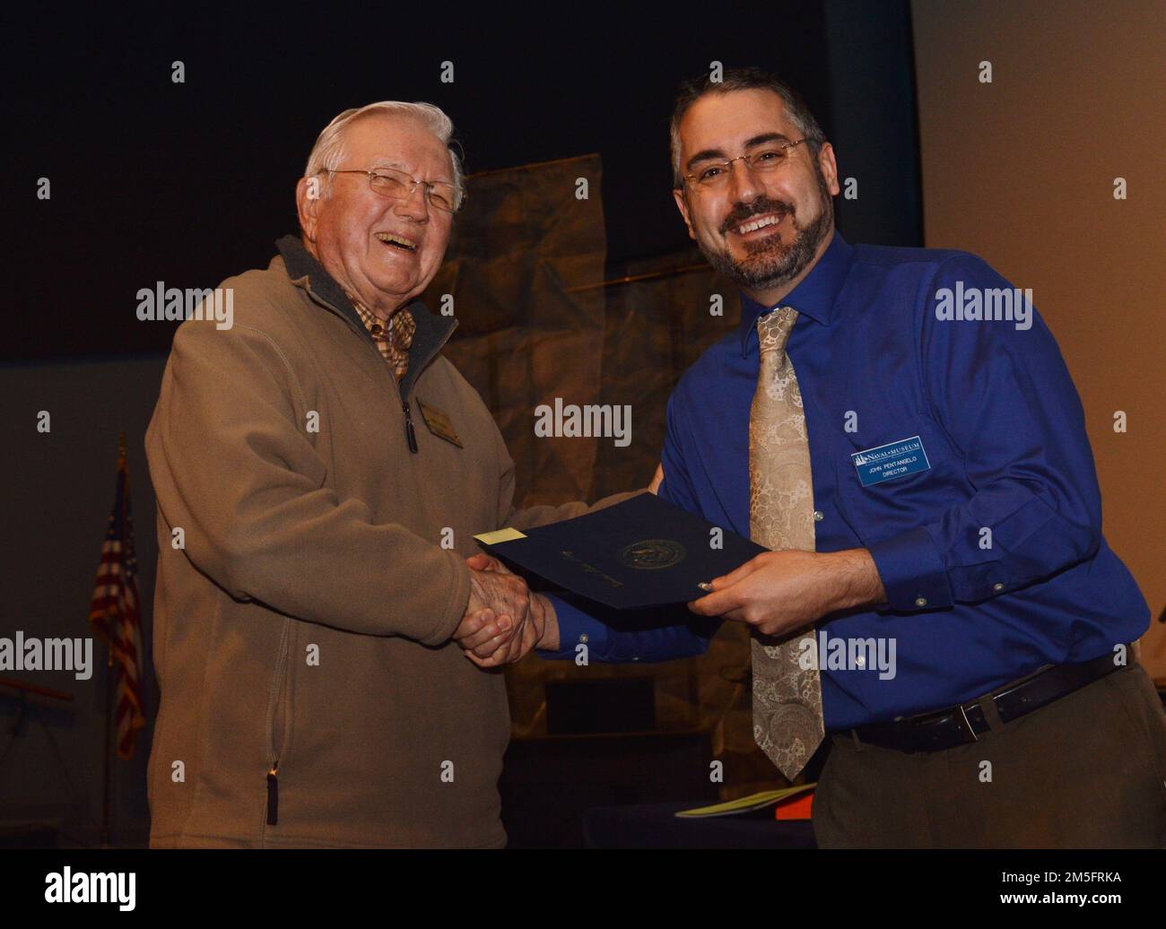 Museum Volunteer Ira Hanna (links) erhält ein freiwilliges Dankeszertifikat von John Pentangelo (rechts), Direktor des Hampton Roads Naval Museum, während einer ehrenamtlichen Veranstaltung. Das Museum befindet sich im zweiten Stock des Nauticus-Gebäudes in Downtown Norfolk, Virginia und ist eines von 10 US-amerikanischen Marinemuseen, die in das Naval History and Heritage Command fallen. Das Museum beherbergt auch ein robustes Freiwilligenkorps. Stockfoto