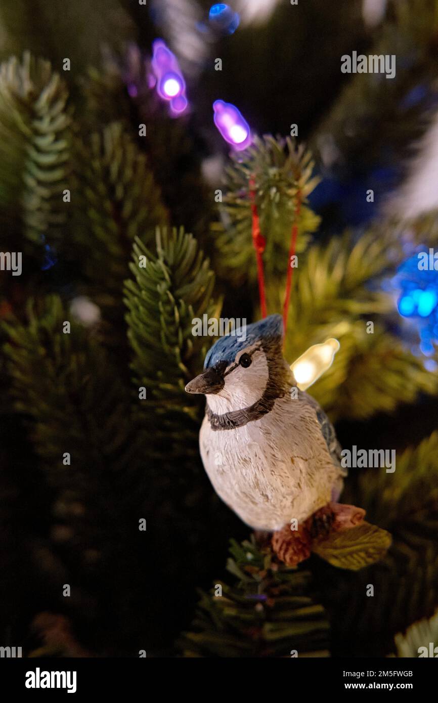 Auf einer künstlichen Tanne ist ein blaues weihnachtsschmuck mit Weihnachtsbeleuchtung im Hintergrund zu sehen. Stockfoto