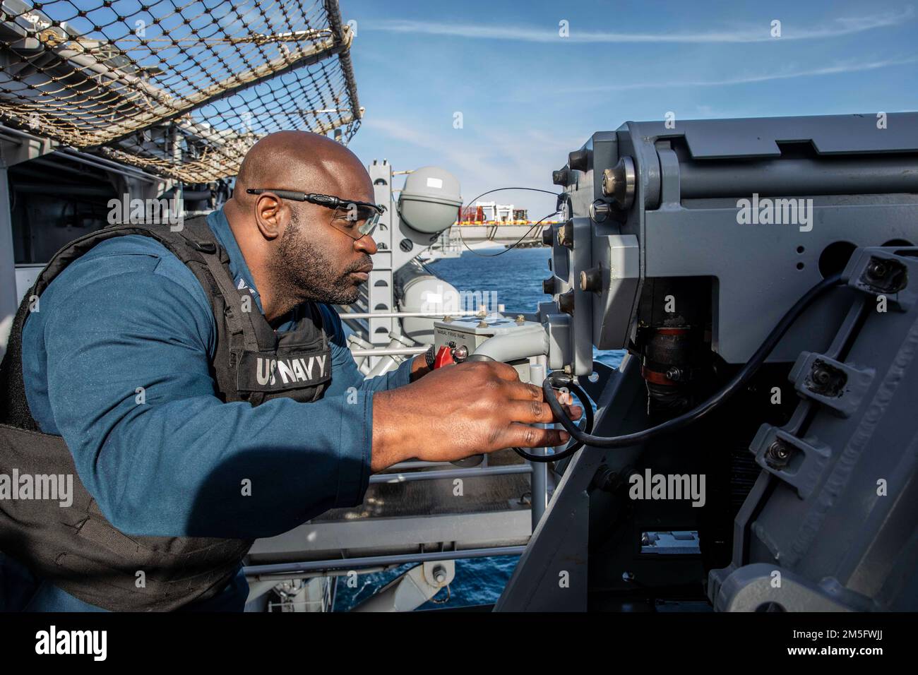 220315-N-XK047-2114 PAZIFIK (15. März 2022) – Aviation Ordnanceman 1. Class Michael Maston beobachtet ein Mark 38 25 mm Maschinengewehrsystem an Bord des Amphibienschiffs USS Makin Island (LHD 8), März 15. Makin Island führt Routineeinsätze in der US-3.-Flotte durch. Stockfoto