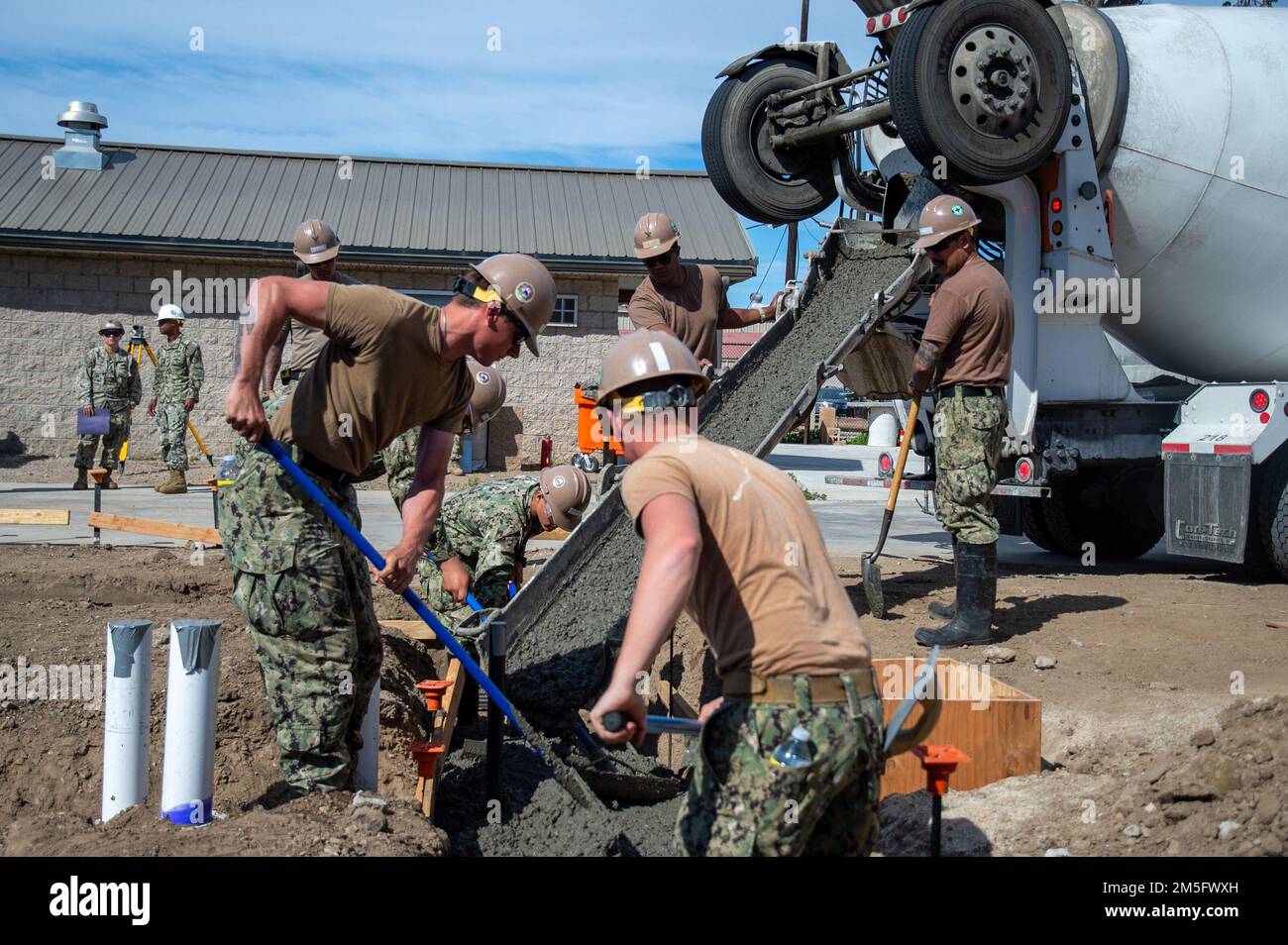 220315-N-MQ841-1037 PORT HUENEME, KALIFORNIEN (15. März 2022) USA Navy Seabees, dem Naval Mobile Construction Battalion (NMCB) 5 zugeteilt, verwenden Rechen, um Beton für die Platzierung von Betonfußböcken zu verteilen, während ein Techniker an Bord der Naval Base Ventura County Port Hueneme, Kalifornien, arbeitet. Die USA Navy Seabees mit NMCB-5 werden aus Port Hueneme heimgeschickt. Sie bilden in hochwertigem Bau, Expeditionslogistik und Kampfeinsätzen aus, um Bau- und Ingenieurprojekte für größere Kampfeinsätze, Katastrophenabwehr und humanitäre Hilfe durchzuführen. Stockfoto