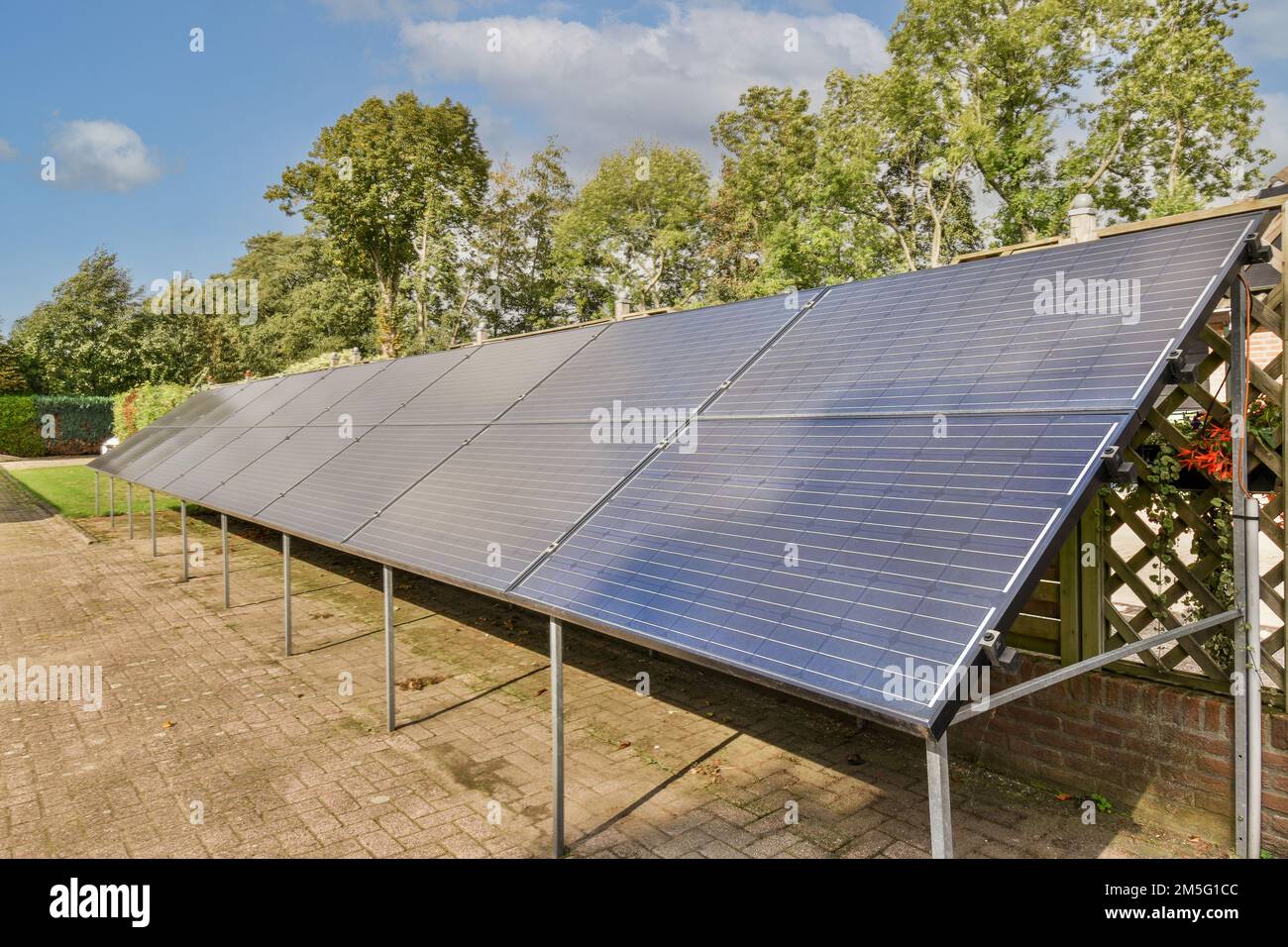 Sonnenkollektoren auf dem Dach eines Hauses mit blauem Himmel und weißen Wolken auf dem Foto werden von hinten aufgenommen Stockfoto