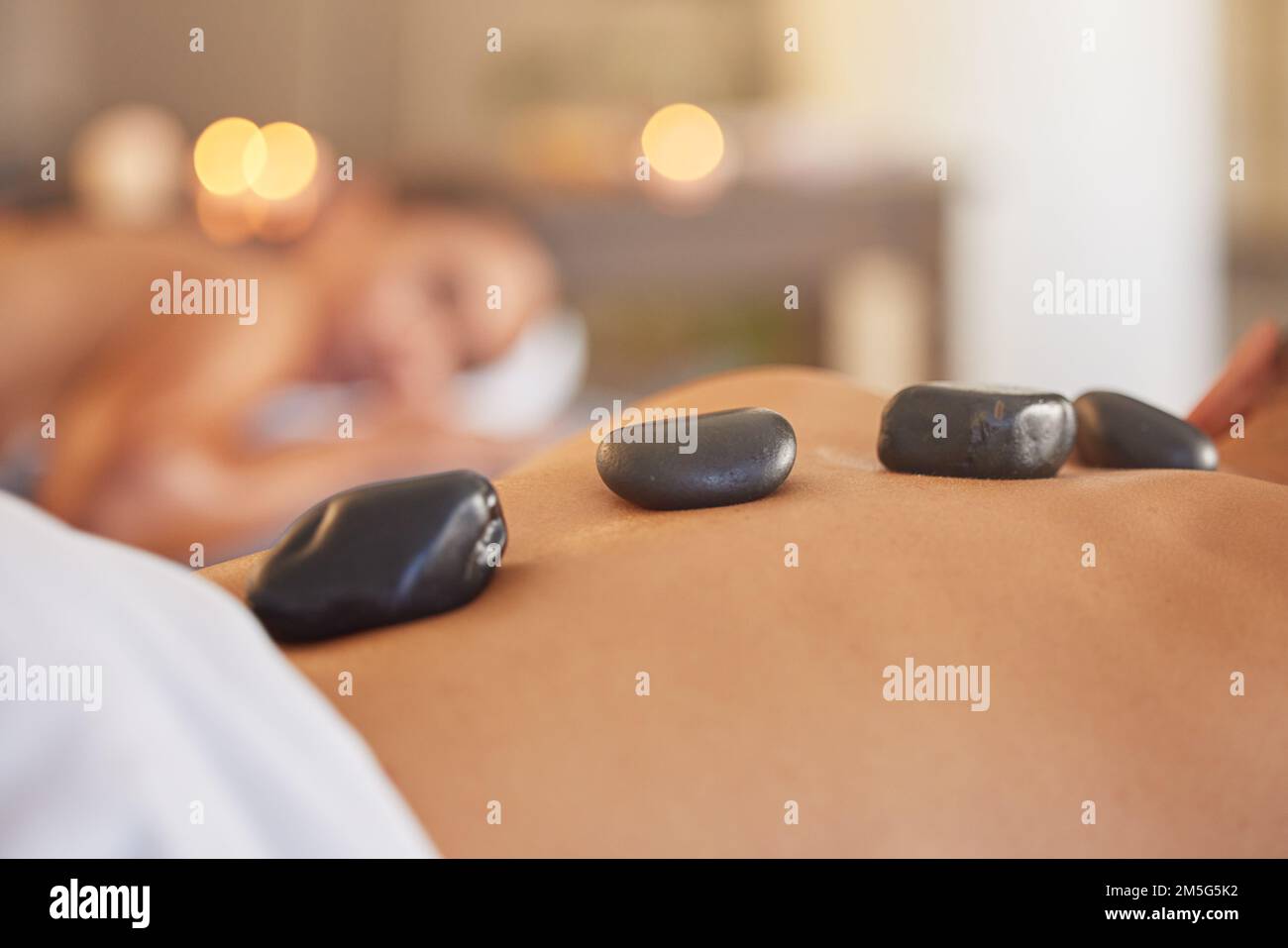 Stone, Mann oder Frau in einem Spa für eine Massage, entspannende Selbstpflege oder luxuriöse Physiotherapie zur Heilung von Rückenschmerzen. Hot-Stone-Massage, Zoom oder Kunde Stockfoto