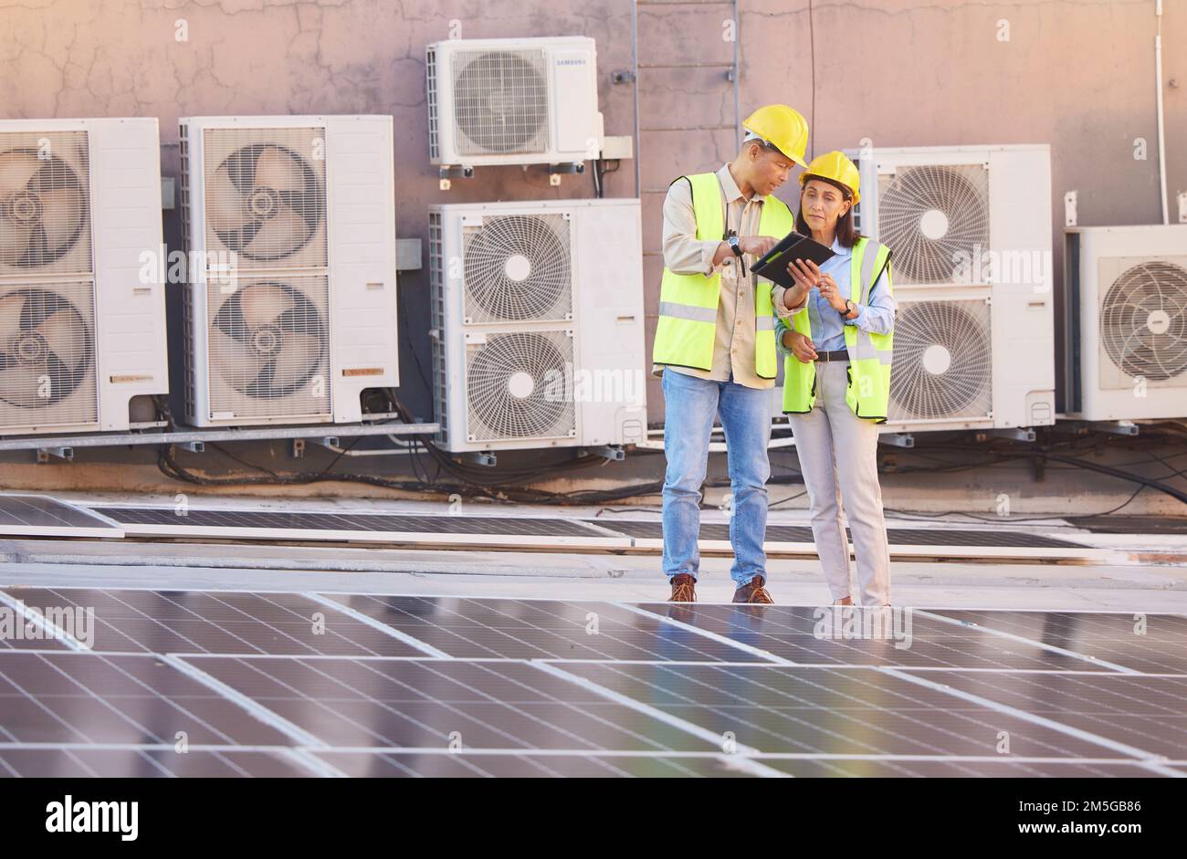 Tablet, Solarenergie oder Ingenieurteam auf dem Dach einer Stadtplanung, die über erneuerbare Energien spricht oder spricht. Solarmodule, Zusammenarbeit oder Stockfoto