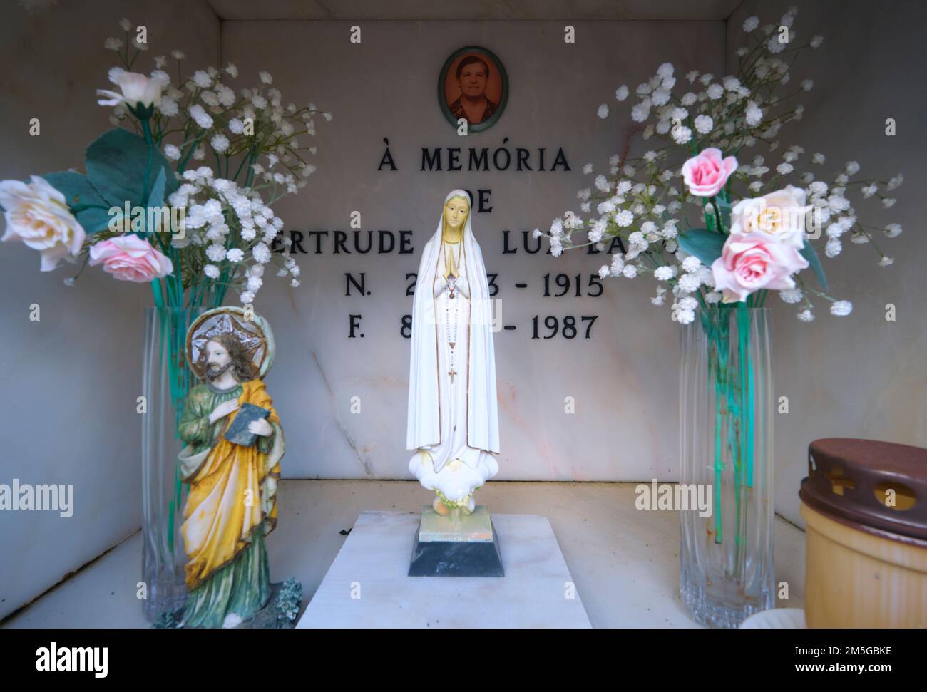 Eine kleine weiße Statue der Jungfrau Maria in einem Grab auf dem katholischen Friedhof. Im Cemitério Paroquial de Vila Nove de Cacela. In der Algarve-Gegend von Stockfoto