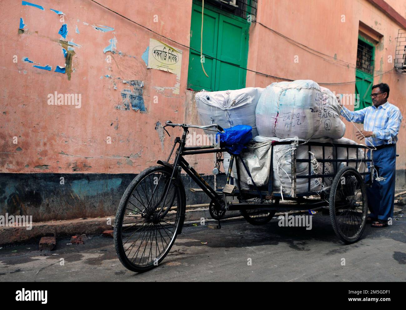 Ein Bengaliser, der große Pakete auf einer Fahrrad-Rikscha in Kalkutta, Indien, transportiert. Stockfoto
