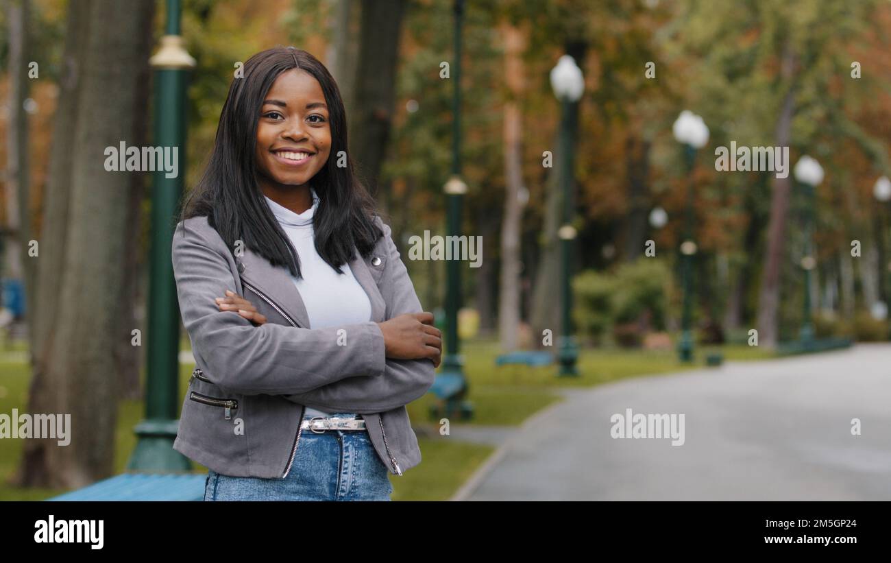 Porträt im Freien eine ethnische Geschäftsfrau, die mit weißen Zähnen auf die Kamera schaut und ein Lächeln in der Zahnheilkunde entwickelt. Afroamerikanisches Mädchen lächelnd Frau im Stehen Stockfoto