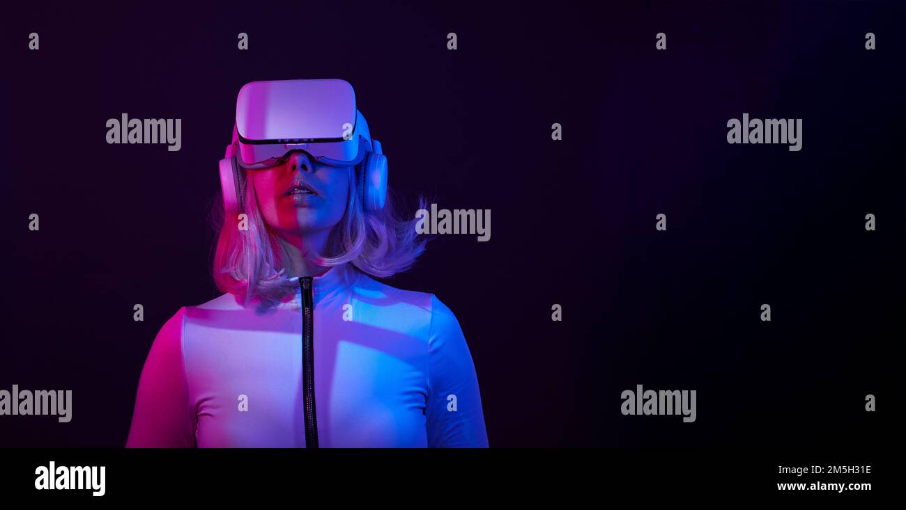 Eine Frau in Virtual-Reality-Brille in Neonfarben. Das Konzept der digitalen Technologie für Metaversum und Unterhaltung der Zukunft. Stockfoto