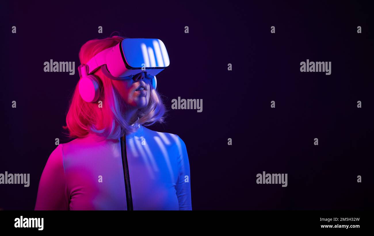 Eine Frau in Virtual-Reality-Brille in Neonfarben. Das Konzept der digitalen Technologie für Metaversum und Unterhaltung der Zukunft. Stockfoto