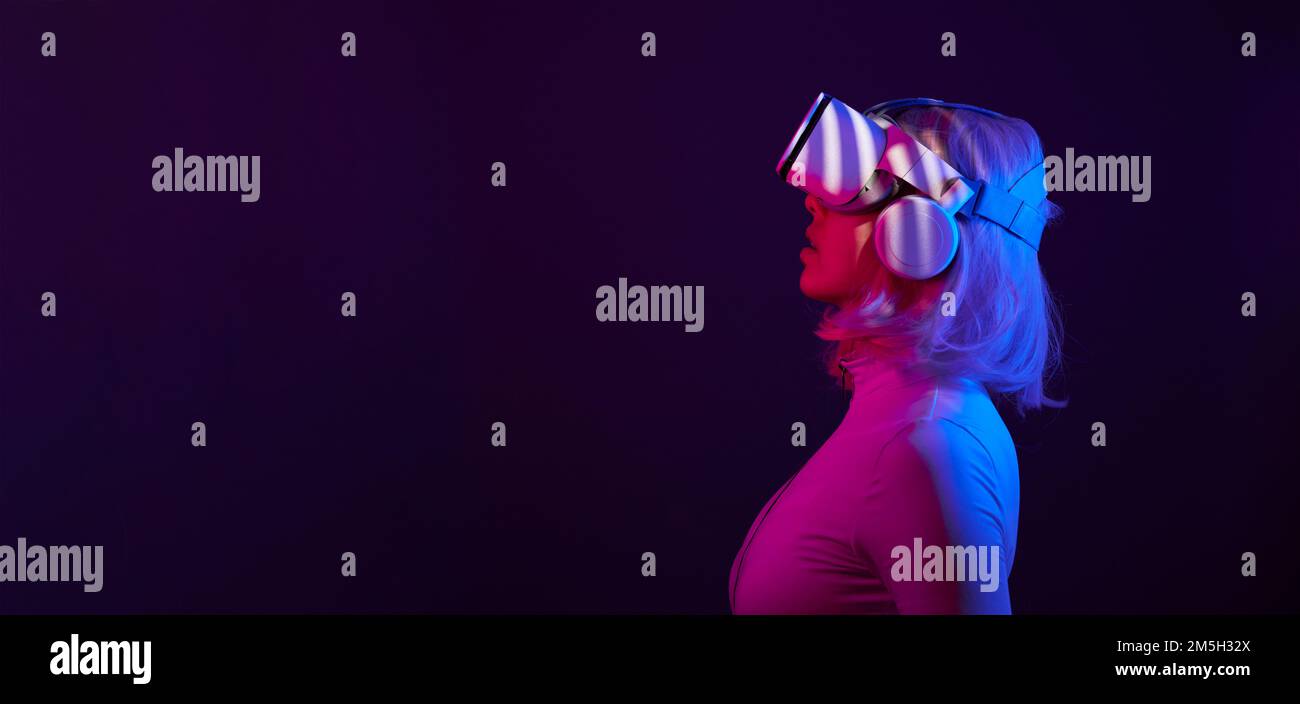 Eine Frau in Virtual-Reality-Brille in Neonfarben. Das Konzept der digitalen Technologie für Metaversum und Unterhaltung der Zukunft. Stockfoto