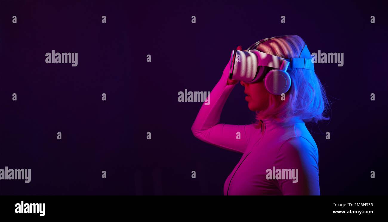 Eine Frau in Virtual-Reality-Brille in Neonfarben. Das Konzept der digitalen Technologie für Metaversum und Unterhaltung der Zukunft. Stockfoto