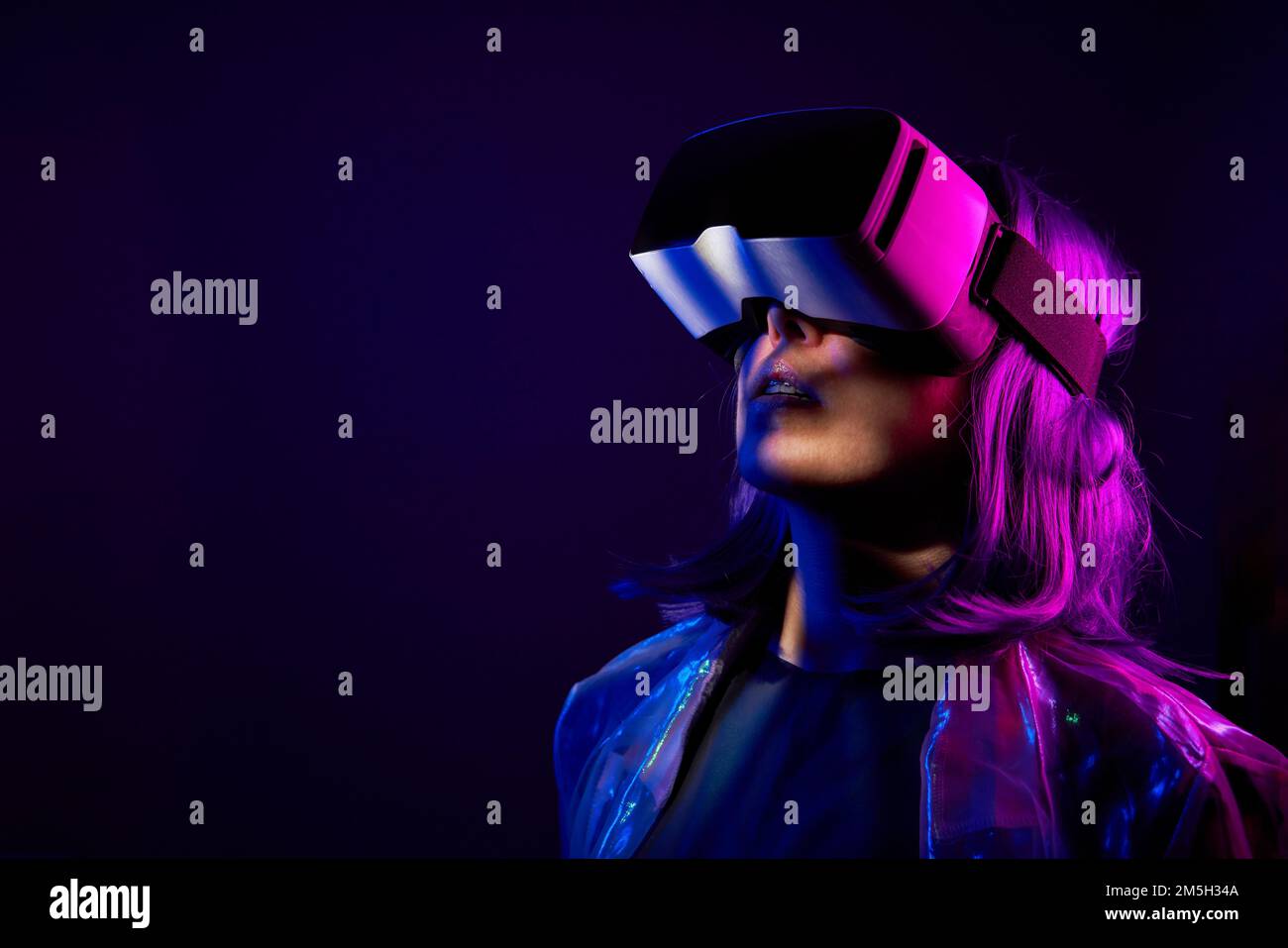 Eine Frau in Virtual-Reality-Brille in Neonfarben. Das Konzept der digitalen Technologie für Metaversum und Unterhaltung der Zukunft. Stockfoto