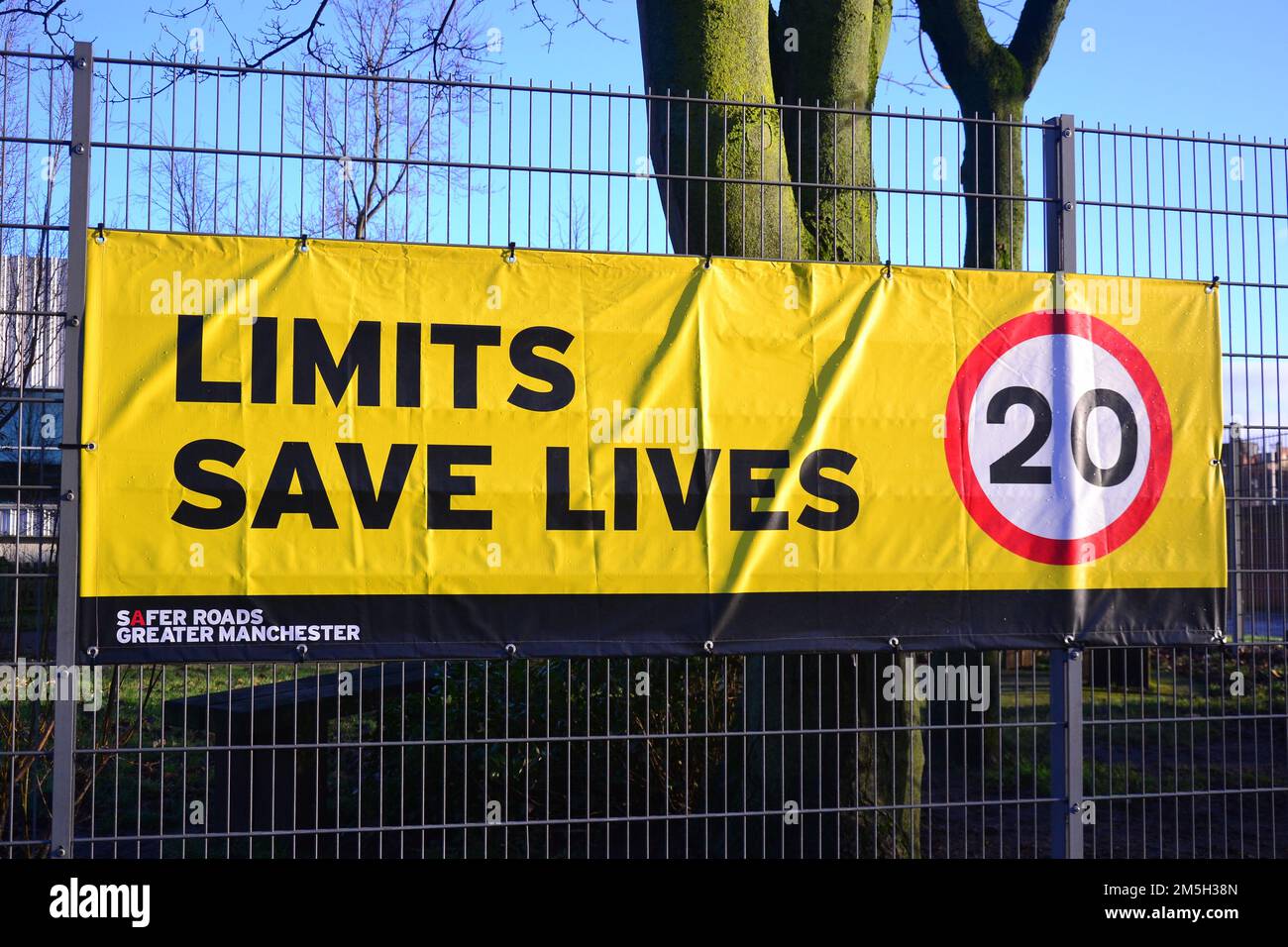 Auf dem Banner für Geschwindigkeitsbegrenzungen steht „Limits Save Lives“ mit einem Vorschlag für 20 km/h am Zaun einer Schule in Manchester, Großbritannien Stockfoto