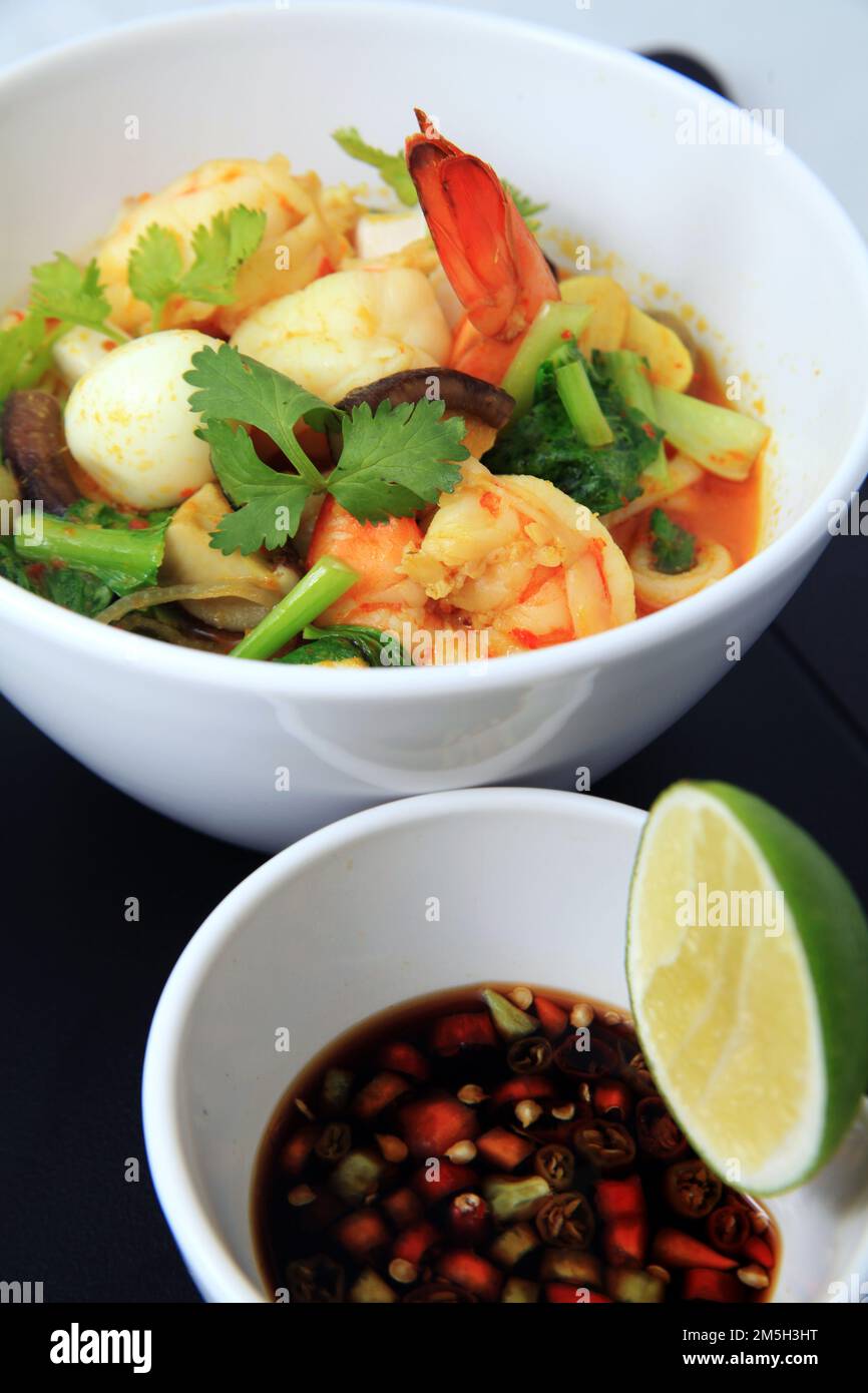 Meeresfrüchte-Garnelen-Curry-Portion in der Schüssel, serviert mit Wachtelei, Gemüse, Limette, Chili in Sojasoße Stockfoto