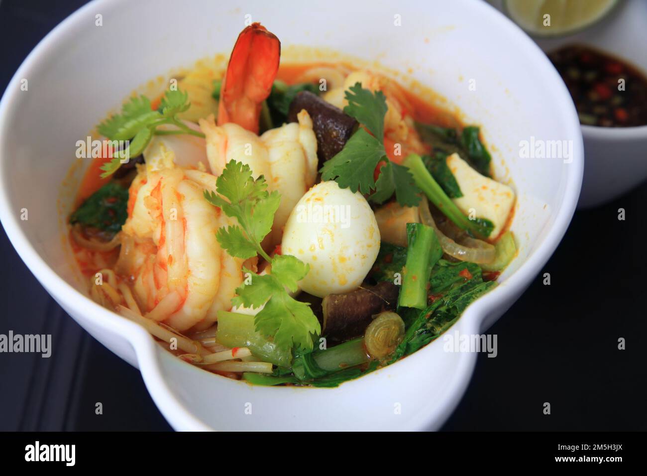 Meeresfrüchte-Garnelen-Curry-Portion in der Schüssel, serviert mit Wachtelei, Gemüse, Limette, Chili in Sojasoße Stockfoto
