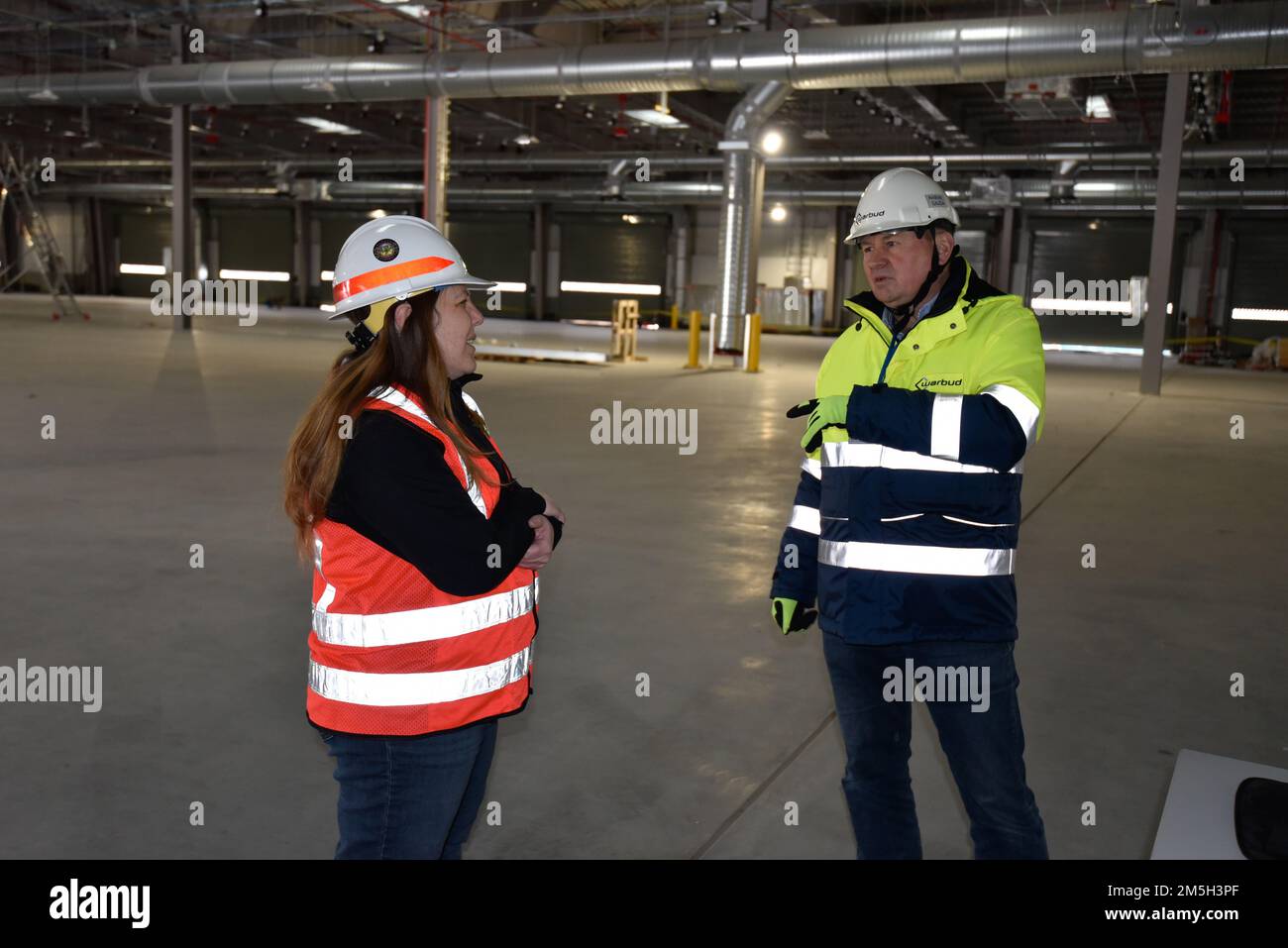 USA Army Corps of Engineers, Europe District Office Engineer Misty Chisum diskutiert den Baufortschritt mit einem Auftragnehmer in einem von mehreren Lagern mit Feuchtigkeitskontrolle, die im Rahmen eines größeren, von der Armee vorpositionierten Aktienprojekts in Powidz, Polen, gebaut werden, am 17. März 2022. Das APS-Projekt umfasst den Bau einer Reihe von feuchtigkeitskontrollierten Lagerhäusern und anderen zugehörigen Einrichtungen zur Lagerung und Wartung von Militärfahrzeugen und -Ausrüstung und ist das größte Projekt in Polen, das vom Nordeuropa-Regionalbüro des Europaberats verwaltet wird. Stockfoto