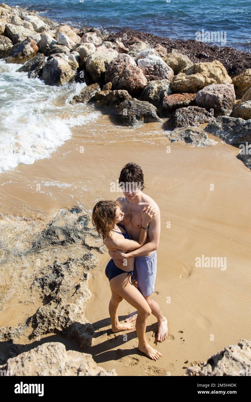 Ein junger Mann und eine Frau, etwa 20 Jahre alt, ein Paar, das sich liebt, in voller Wucherung, die sich sanft am Strand umarmt. Freude am Moment, zärtliche Gefühle, Vergnügen Stockfoto