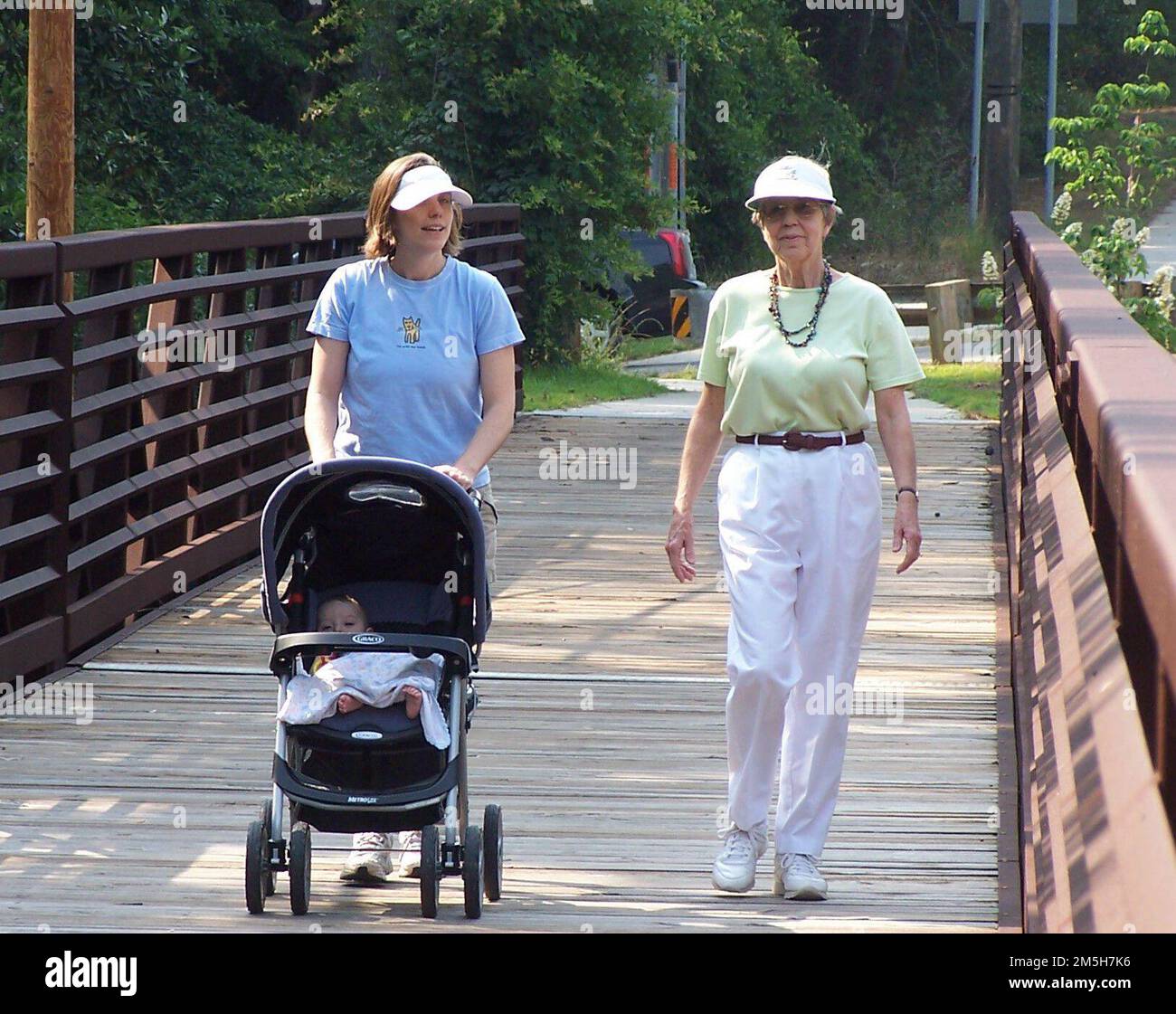 Alabama's Coastal Connection - Spaziergang entlang des Eastern Shore Trail. An einem sonnigen Tag können sich die Walker mit einem Kinderwagen unterhalten und über eine schattige Brücke auf dem Eastern Shore Trail schlendern. Lage: Eastern Shore Trail, Alabama Stockfoto