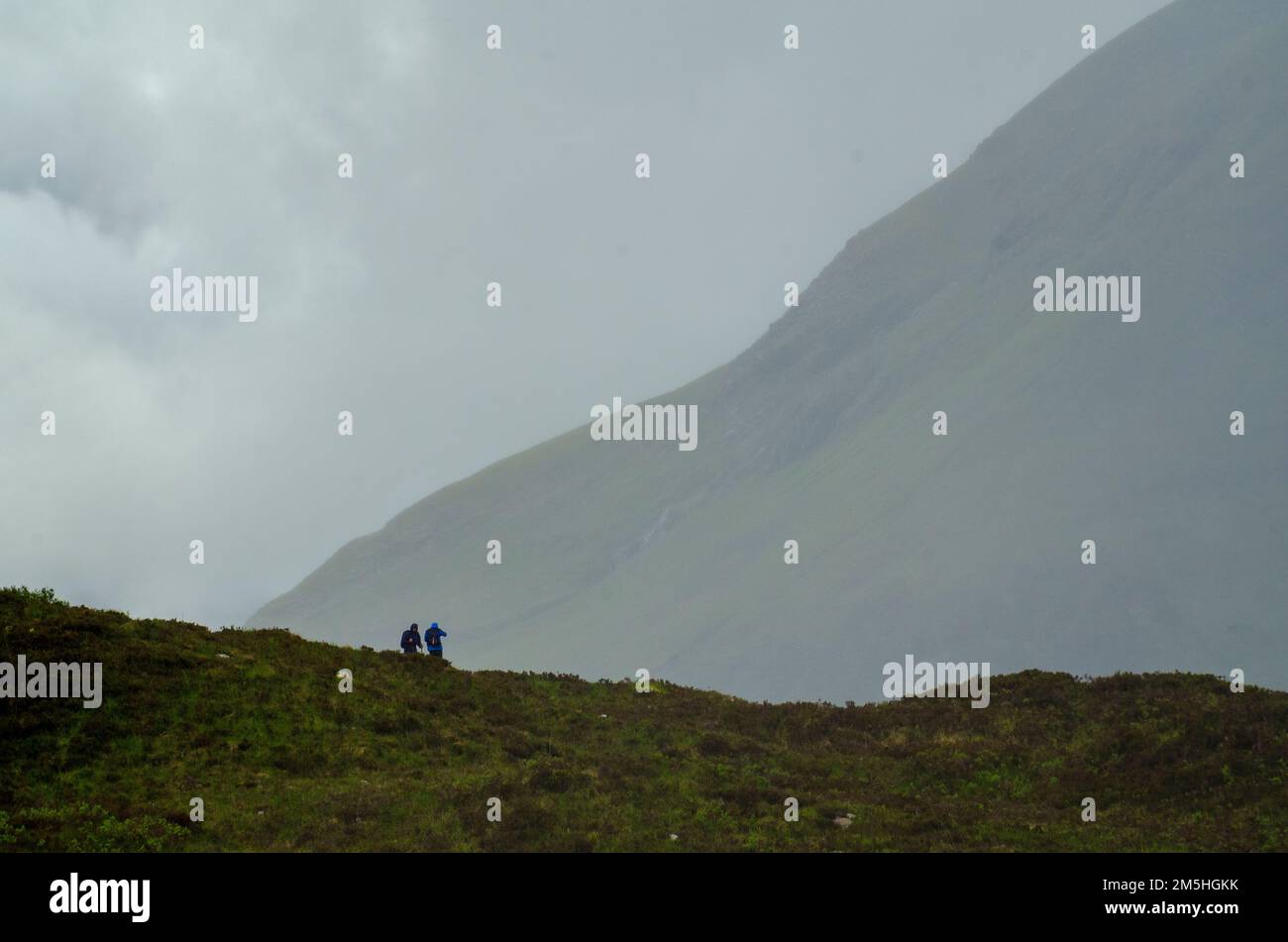 Zwei Trekker ertragen das regnerische Frühlingswetter auf einem Pfad in den Red Cullins auf den Isles of Skye, Schottland, Großbritannien Stockfoto