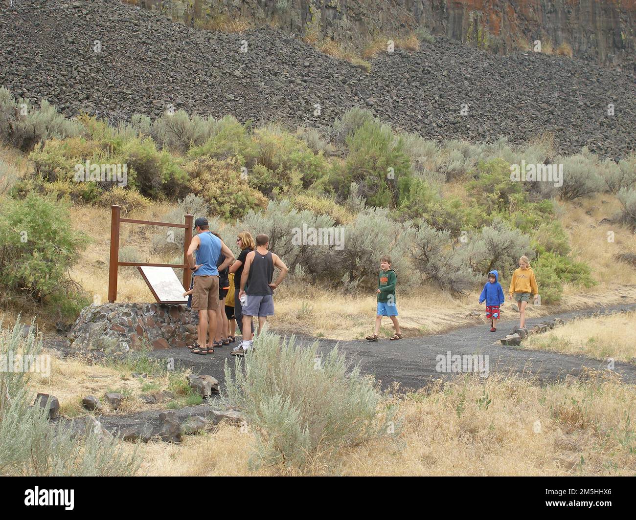 Coulee Corridor Scenic Byway - Lake Lenore Caves Trailhead. Eine Gruppe von Besuchern am Lake Lenore Caves Trailhead liest ein Schild mit Informationen über die Lake Lenore Caves, von denen sieben über den Hauptweg erreichbar sind. Lage: Lake Lenore Caves State Park, Washington (47,607° N 119,366° W) Stockfoto