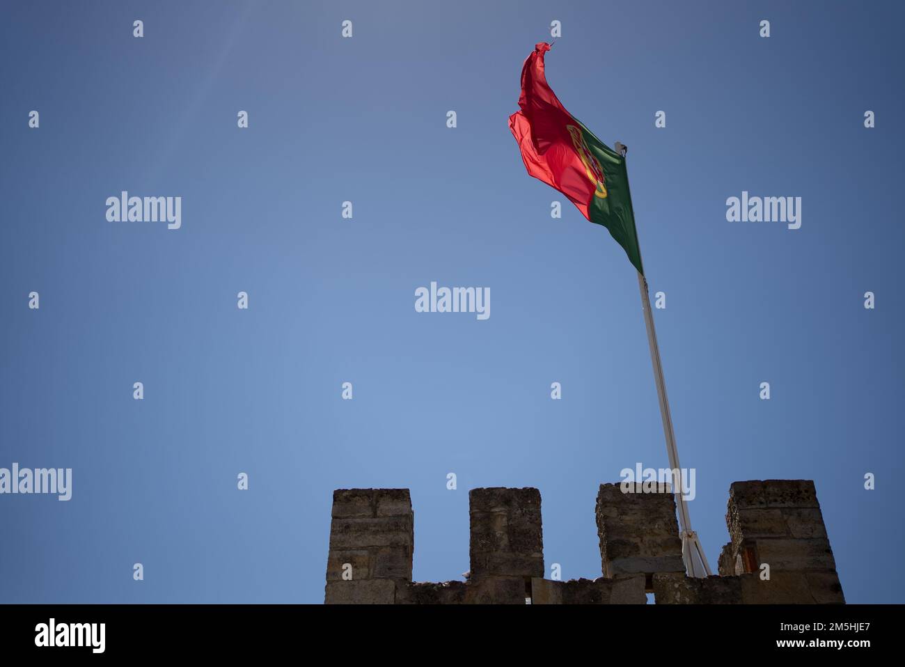 Portugiesische Flagge, die im Wind weht, mit einer Kastenspitze dahinter Stockfoto
