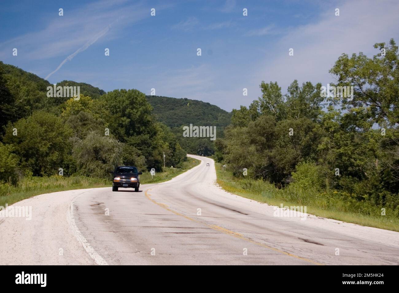 Historic Bluff Country Scenic Byway - Richtung Westen in der Nähe von Mound Prairie. Ein Auto nähert sich dem Historic Bluff Country Scenic Byway in der Nähe des Mound Prairie Scientific and Natural Area. Nahe Mound Prairie, Minnesota (43,766° N 91,423° W) Stockfoto