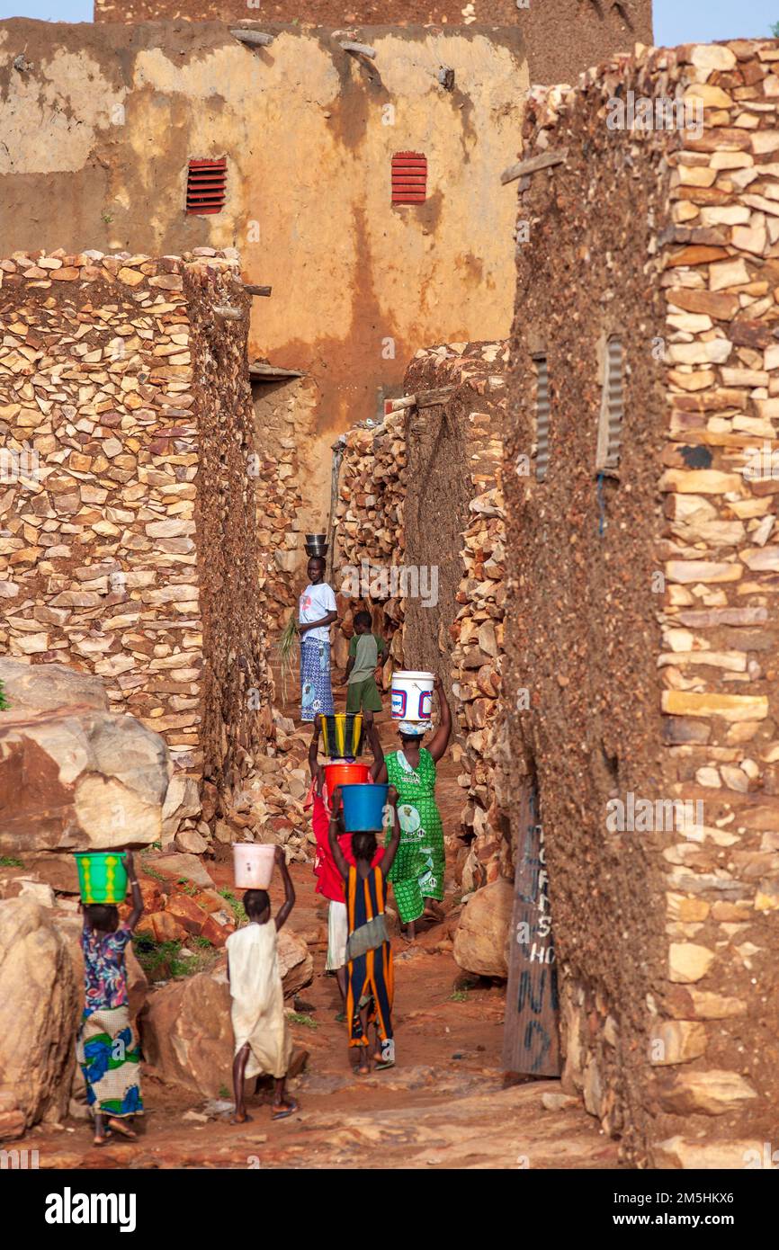 Afrikanische Kinder, die Wasser zu ihren Häusern in der Gegend Hombori, Mali, Westafrika transportieren. Fast 1 Milliarden Menschen weltweit haben keinen Zugang zu sauberem Wasser. Stockfoto