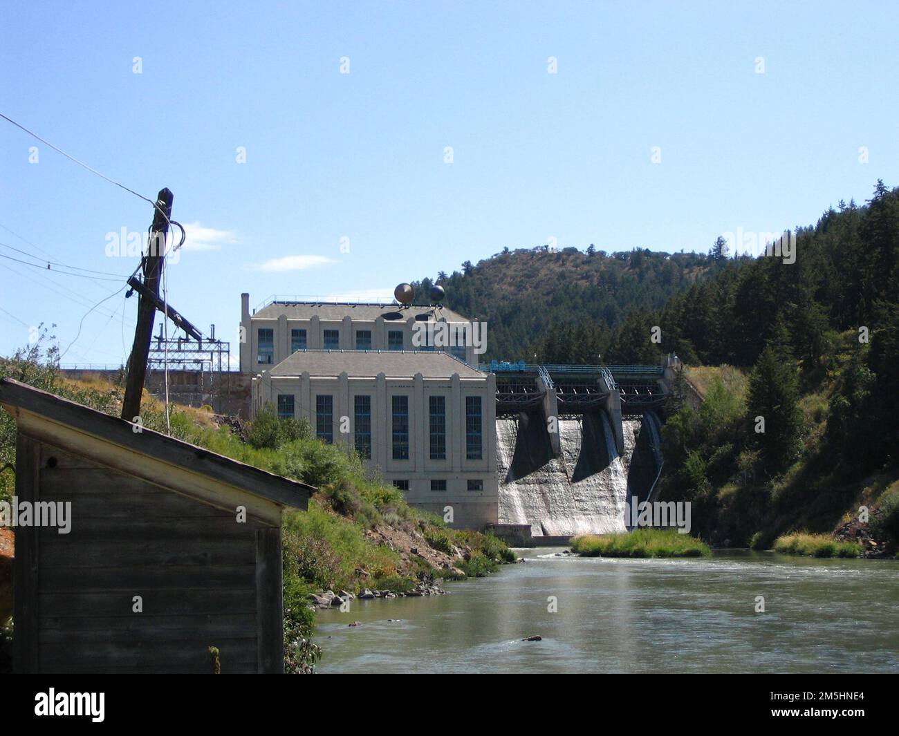 Pioneer Historic Byway - Hells Canyon Dam. Dieser Damm für das Hells Canyon Reservoir reguliert das Wasser. Berge bilden eine Seite des Flusses und das weiße Kraftwerk steht neben dem Damm. Lage: Hells Canyon Dam, Idaho (45,244° N 116,701° W) Stockfoto