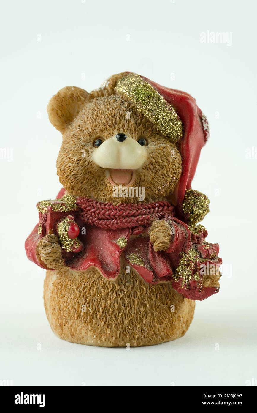 Süße Bärenfigur mit Geschenken und Weihnachtsmannmütze auf weißem Hintergrund Stockfoto