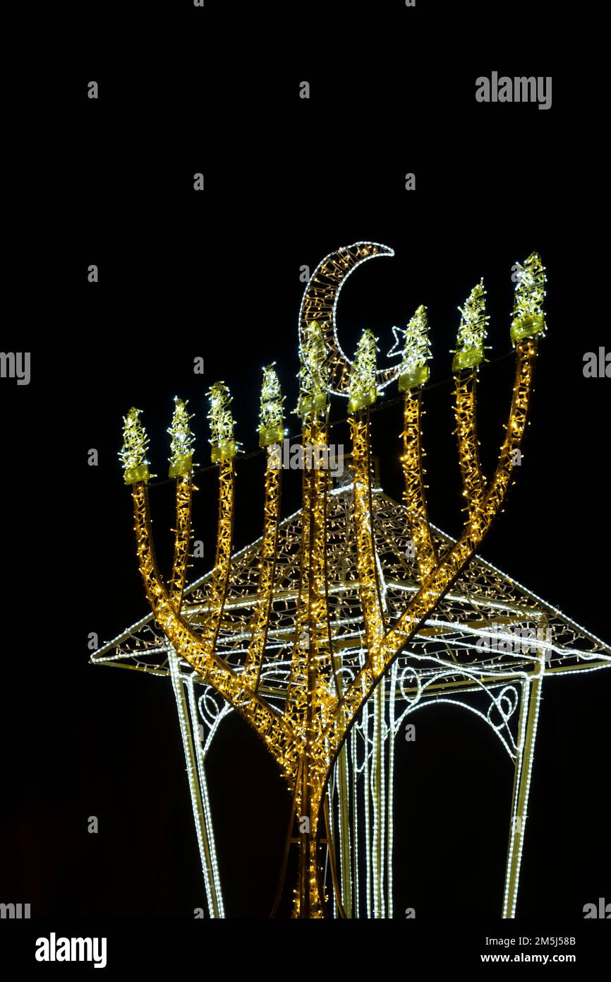 Die erleuchtete Menorah Hanukkah und der Halbmond des Neumunds, der mit dem Islam assoziiert ist, werden im deutschen Kolonialviertel in Haifa, Israel, gezeigt, während die Stadt den Feiertag feiert, an dem die Chanukka, Weihnachten und Ramadan Feiertage von drei großen Religionen begangen werden: Christentum, Judentum und Islam. Stockfoto