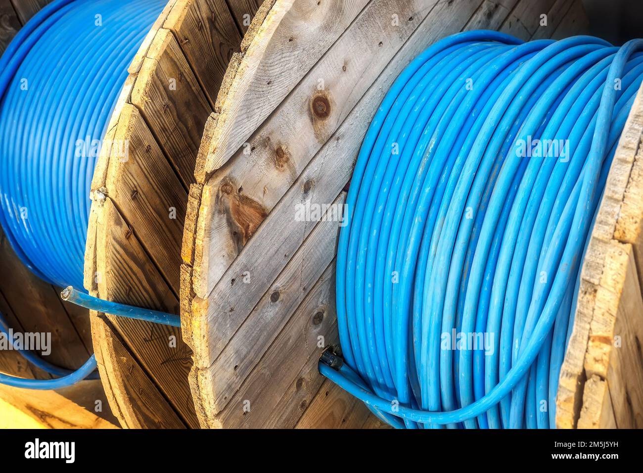 Neues blaues Netzkabel ist auf Holzwicklung gewickelt. Hintergrund. Kabel zur Verlegung unter Tage.. Stockfoto