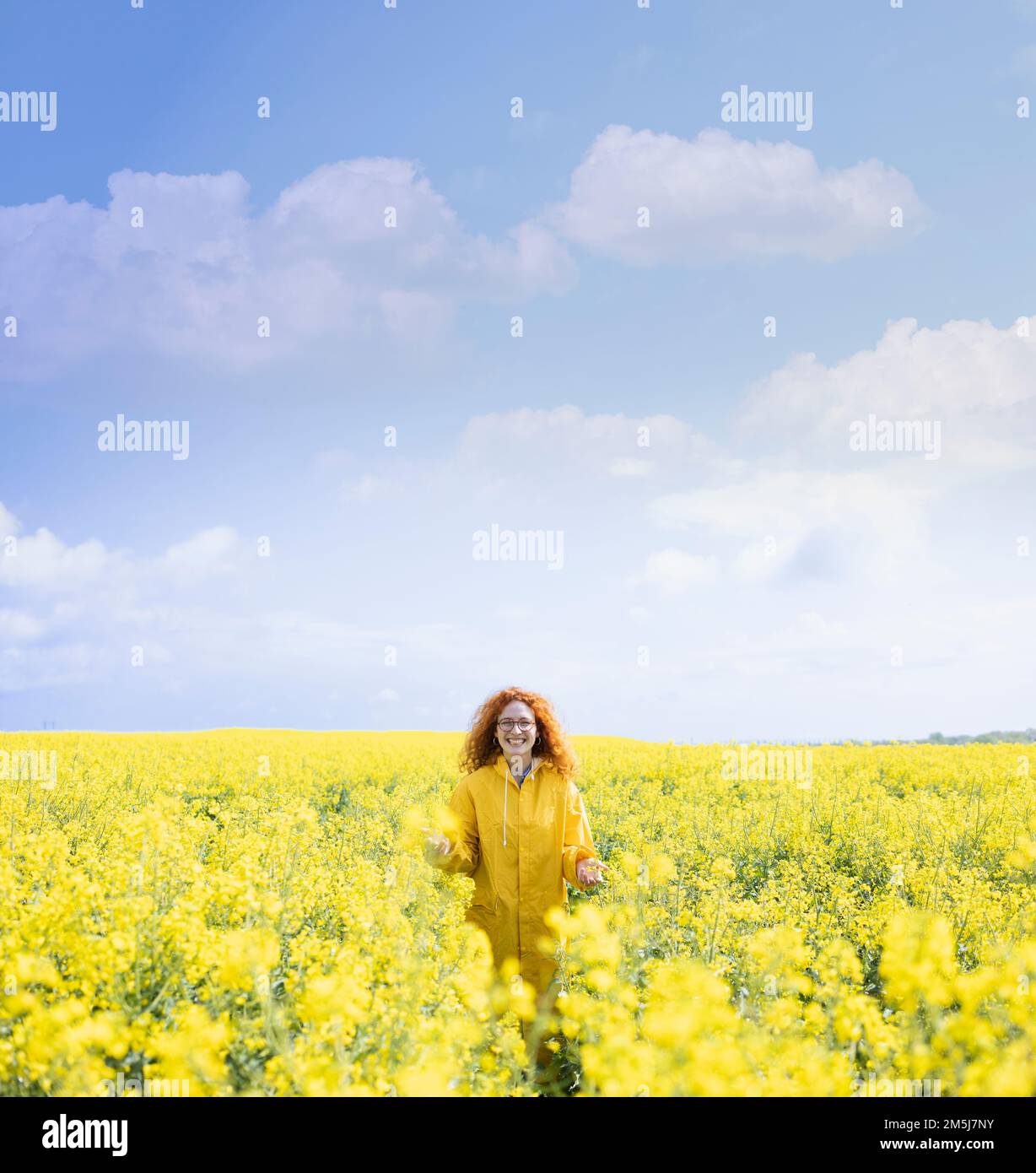 Eine Frau in einem gelben Regenmantel, genießt ihren Frühlingstag Stockfoto